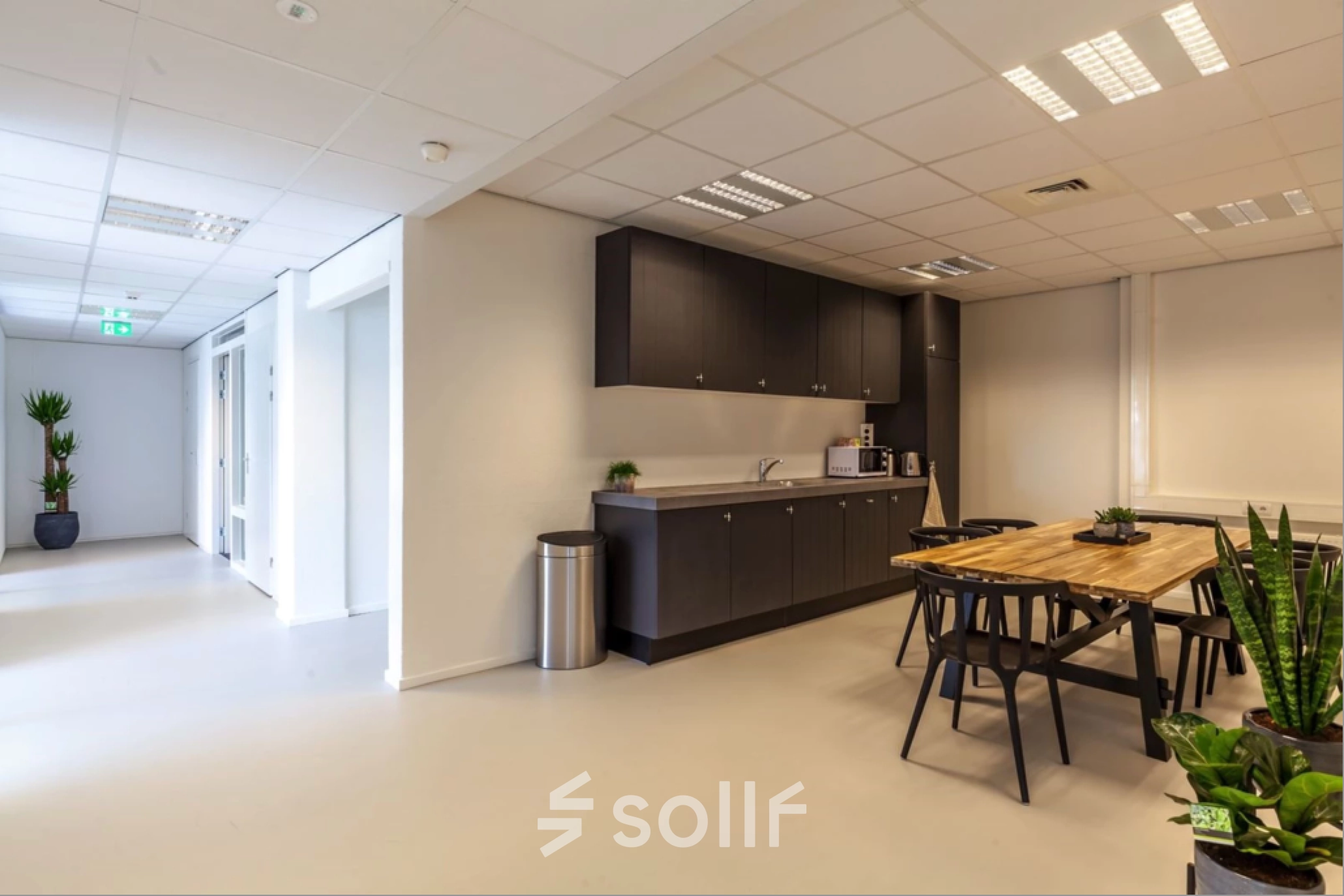 Modern Utrecht Lage Weide office space rental featuring a kitchenette and wooden dining table with chairs, offering a cozy workspace environment.