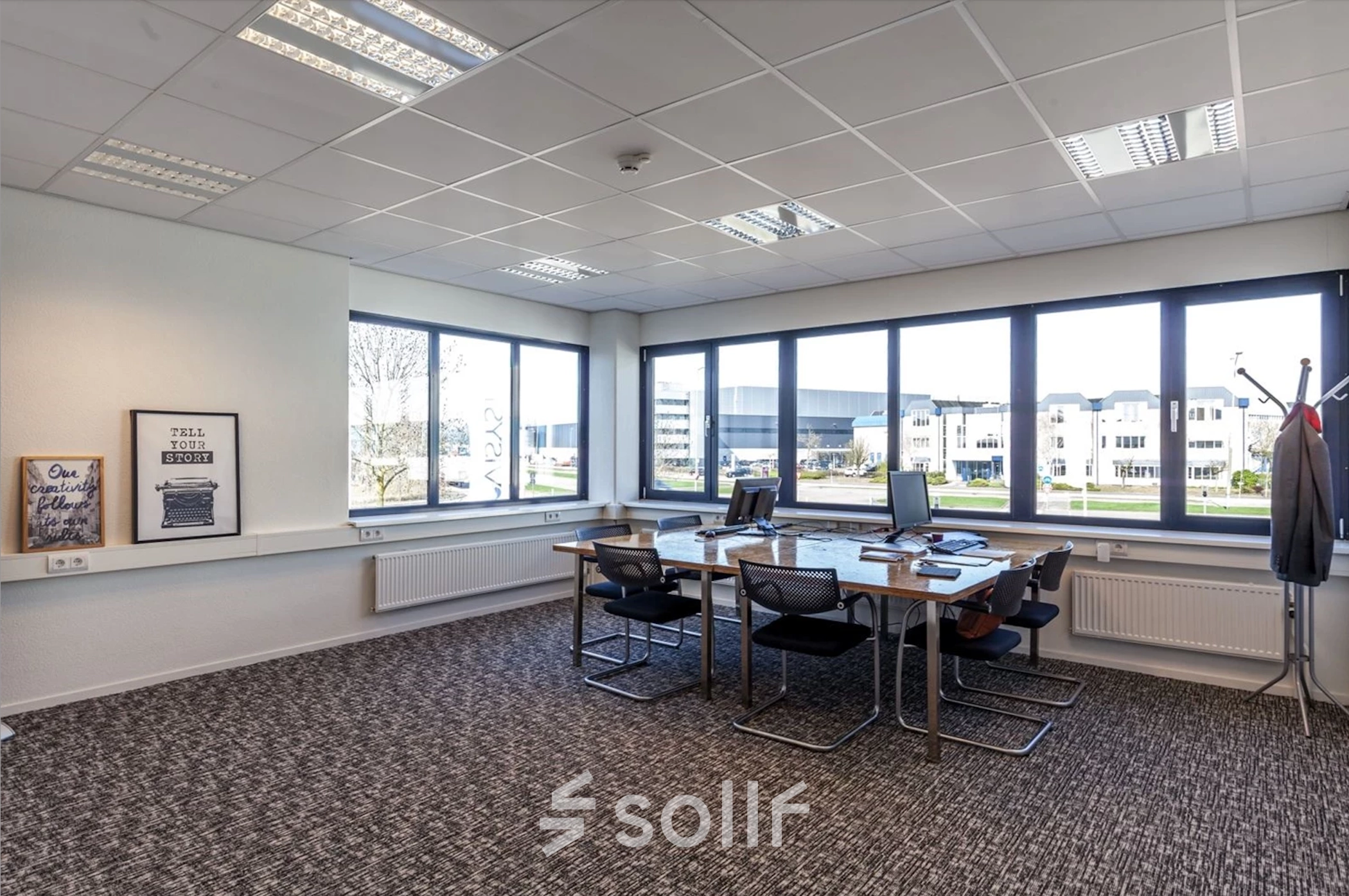 Bright office space with large windows, four desks, computers, and a coat rack in Reactorweg 301, suitable for office space rental in Utrecht Lage Weide.