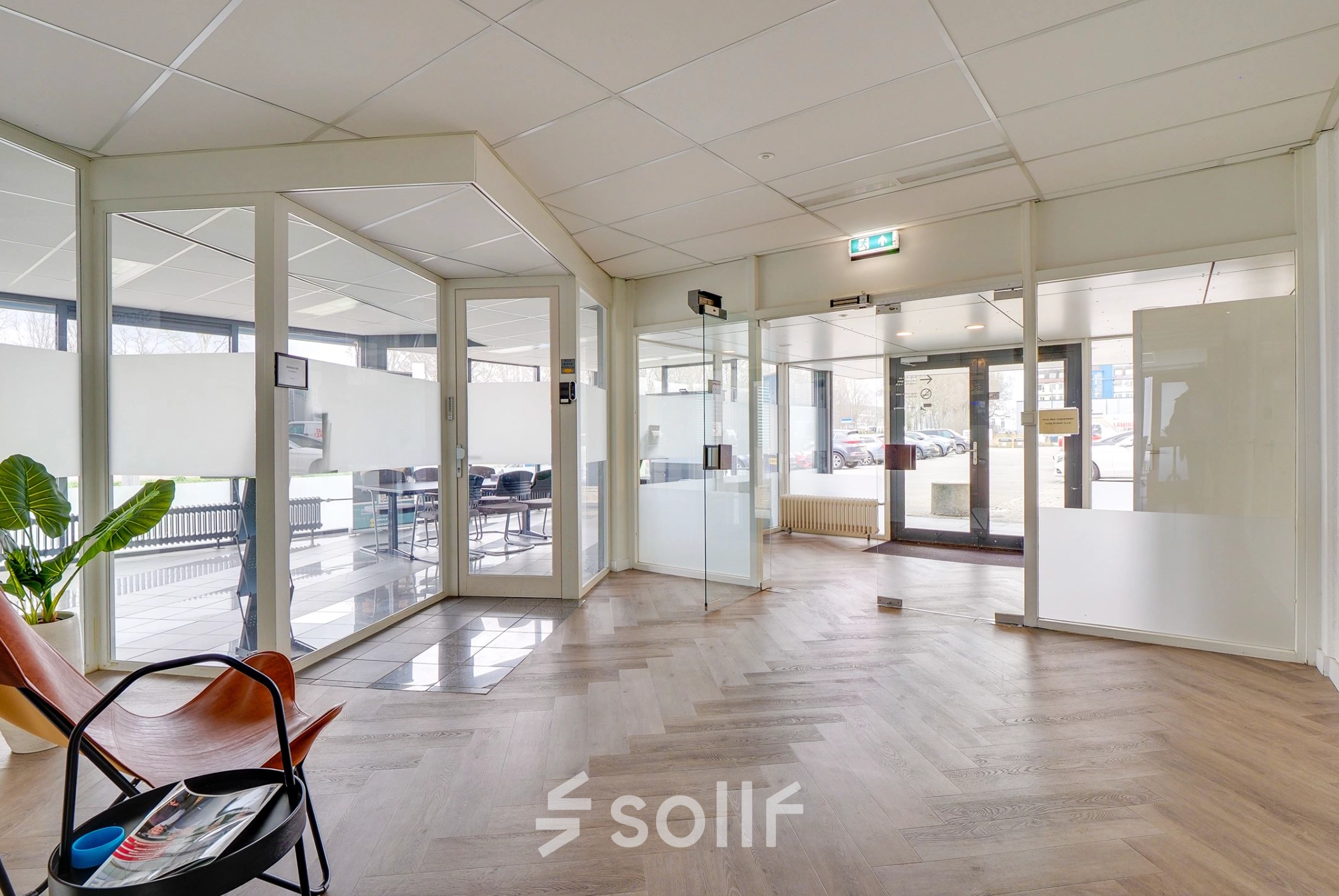 Bright office space at Zonnebaan 18, Utrecht Lage Weide with glass walls and wooden flooring, featuring a few chairs and a plant, ideal for office space rental.