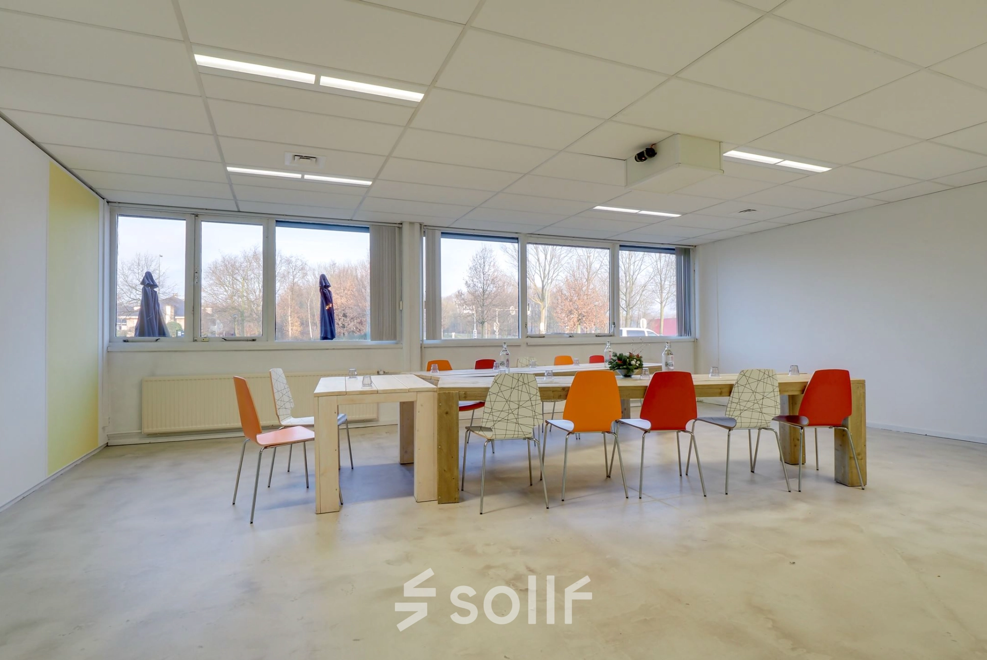 Bright office to rent in Utrecht Lage Weide at Zonnebaan 18, featuring large windows and a spacious table with colorful chairs, ideal for meetings.