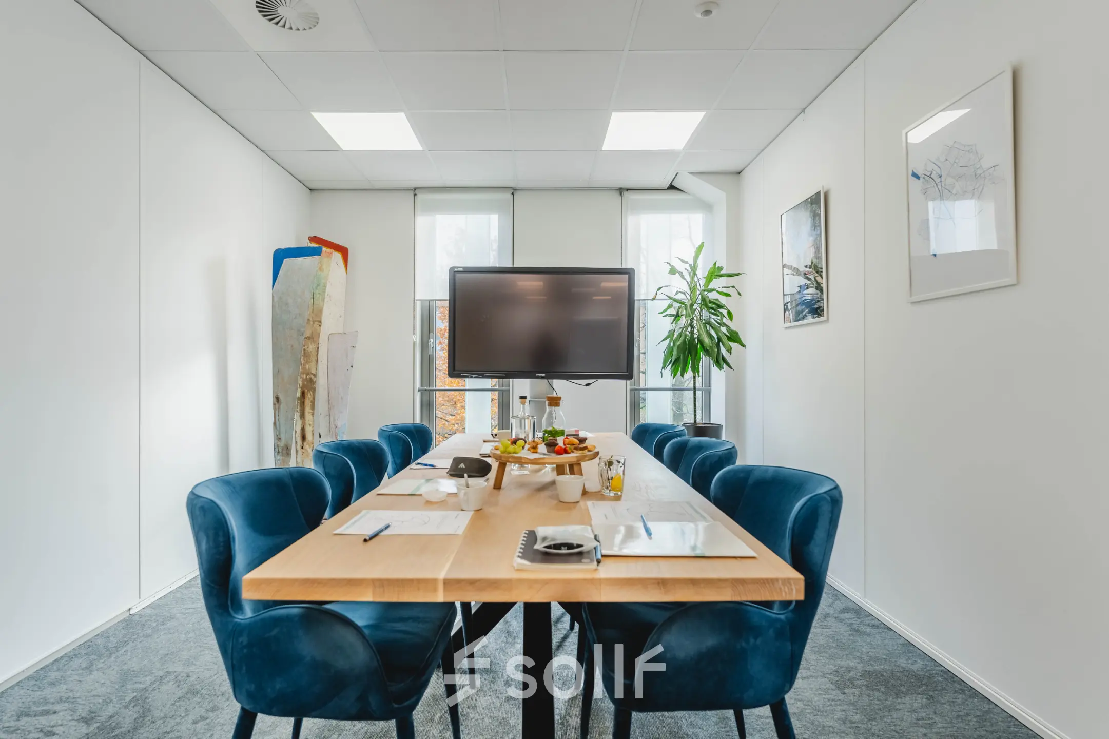Bright office space rental at Orteliuslaan 850, Utrecht Papendorp, featuring a furnished conference room with a modern table, blue chairs, a large screen, and natural light through large windows.