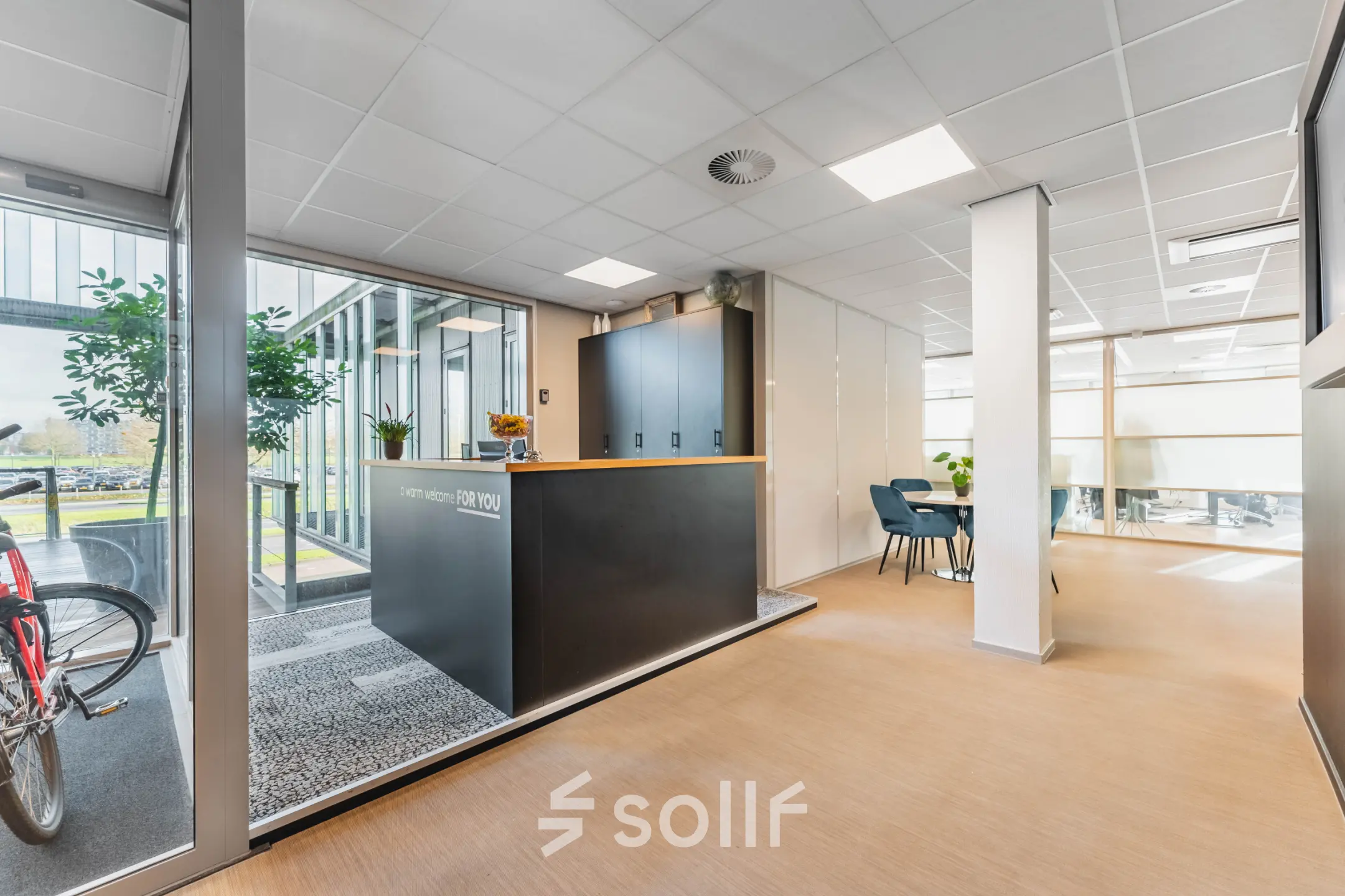 Modern office space rental in Utrecht Papendorp, Orteliuslaan 850, featuring a stylish reception area, furnished with a desk and seating. Bright natural light from large windows enhances the welcoming atmosphere.