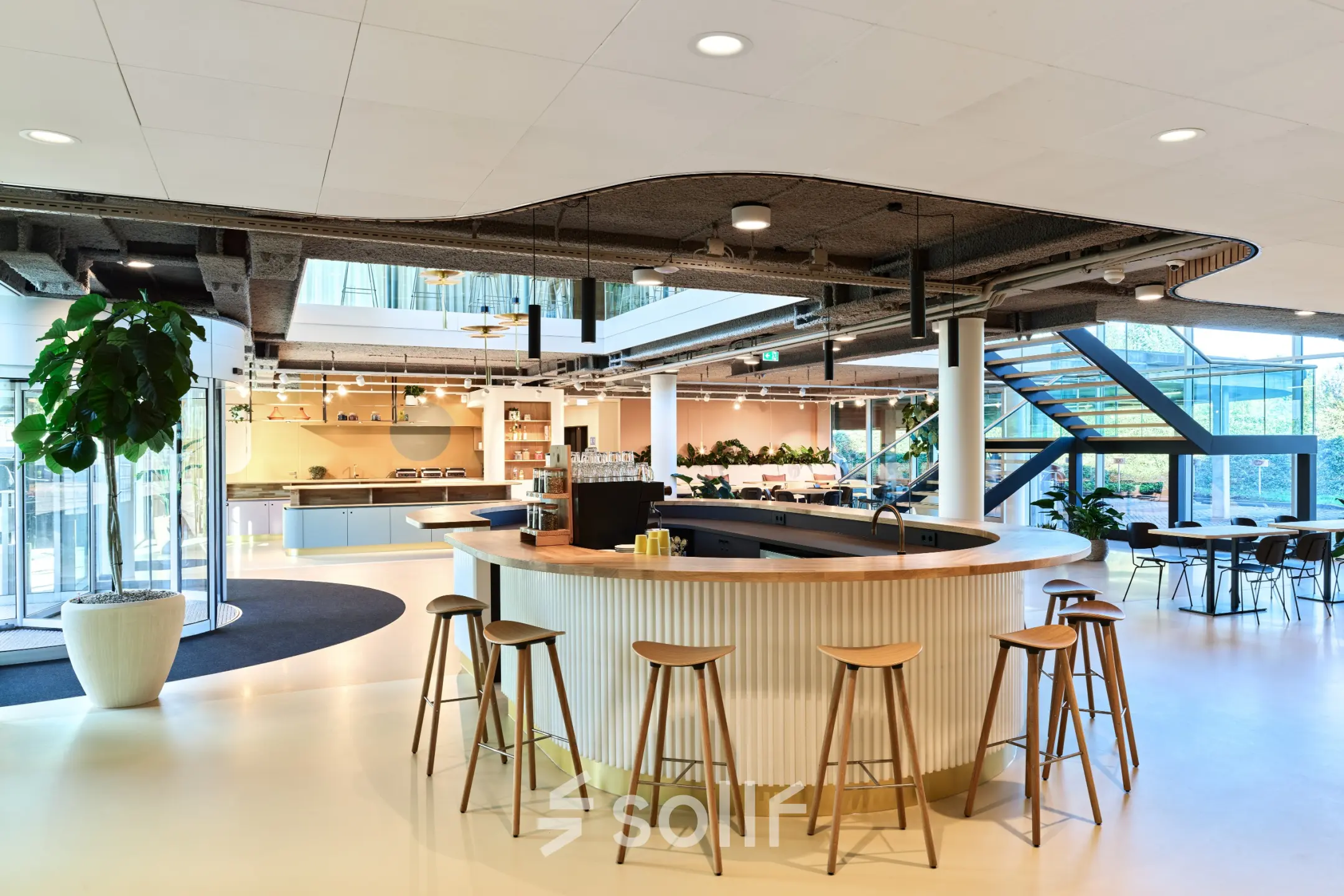 Modern open floor plan with a circular bar, stools, and natural light at Van Deventerlaan 30-40 in Utrecht Papendorp for office space rental.