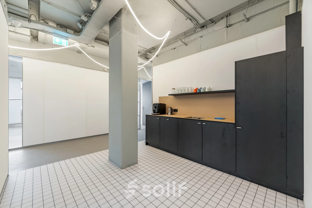 Interior view of a furnished office pantry with a sleek black counter and coffee machine, located at Daltonlaan 200, Utrecht Rijnsweerd, ideal for those seeking office space rental.