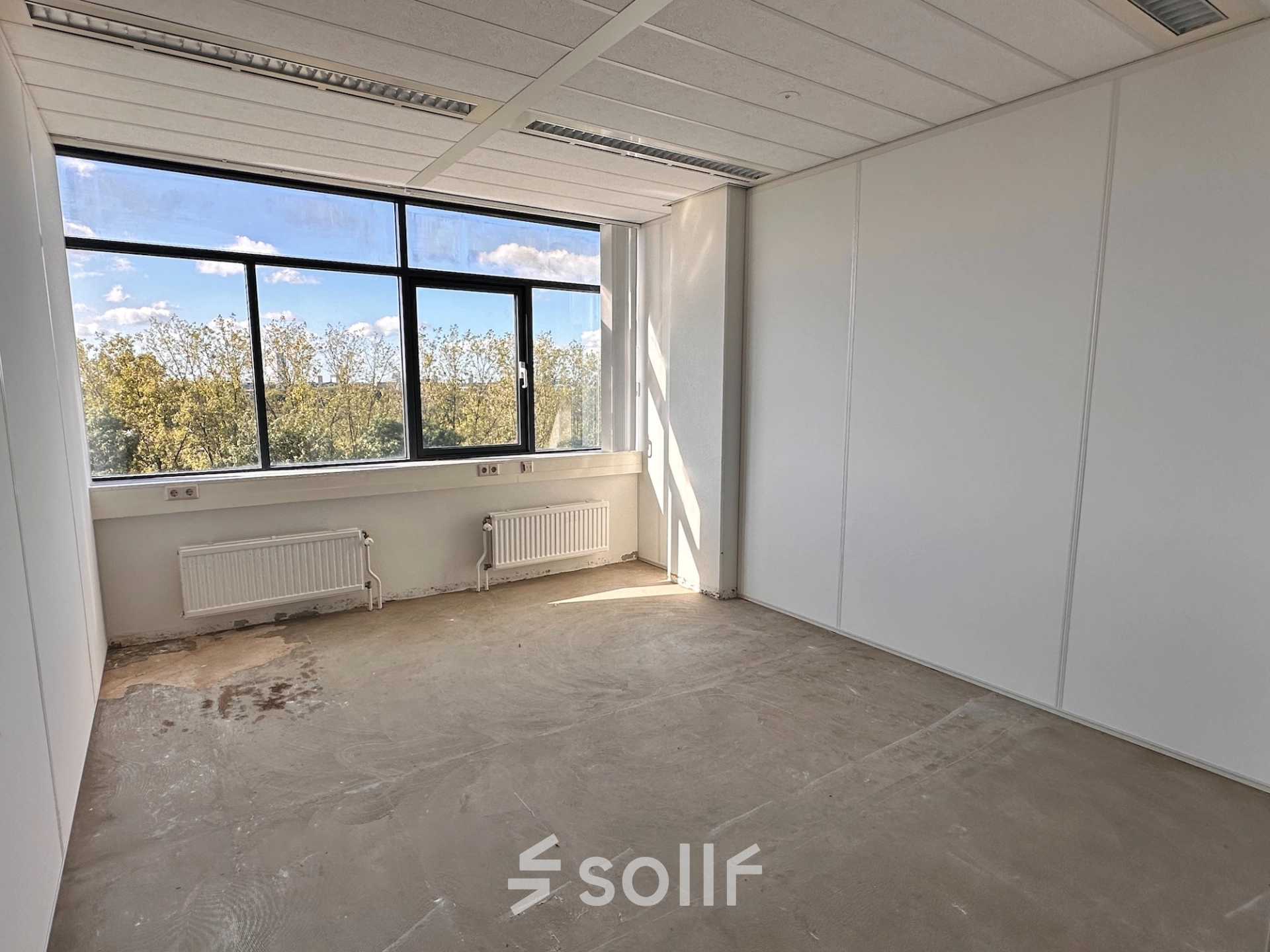 Unfurnished office space with large window overlooking trees, located at Daltonlaan 200, Utrecht Rijnsweerd, available for rent.