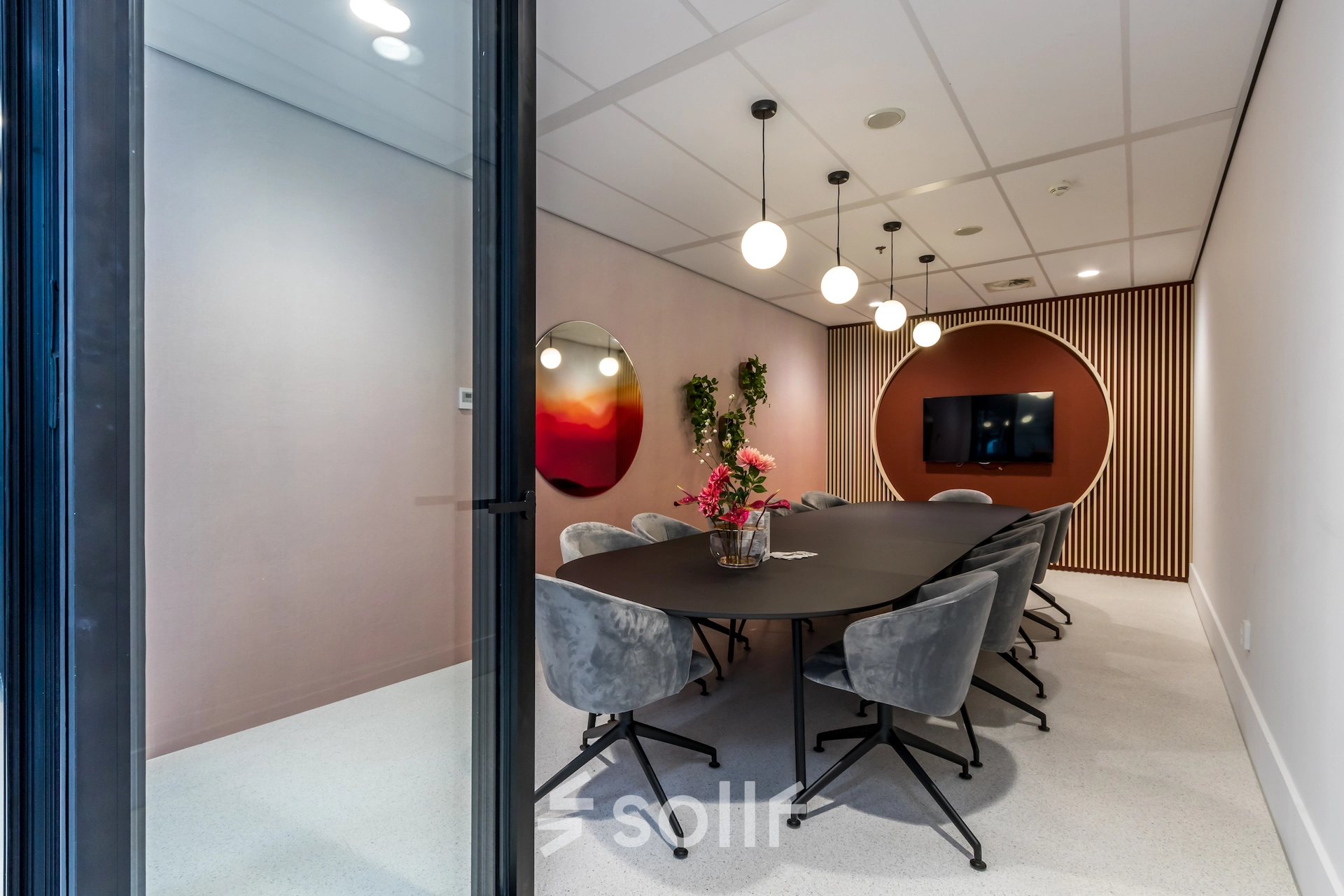 Modern conference room with a long table and stylish chairs, ready for office to rent in Utrecht South. Includes a TV screen and decorative elements.