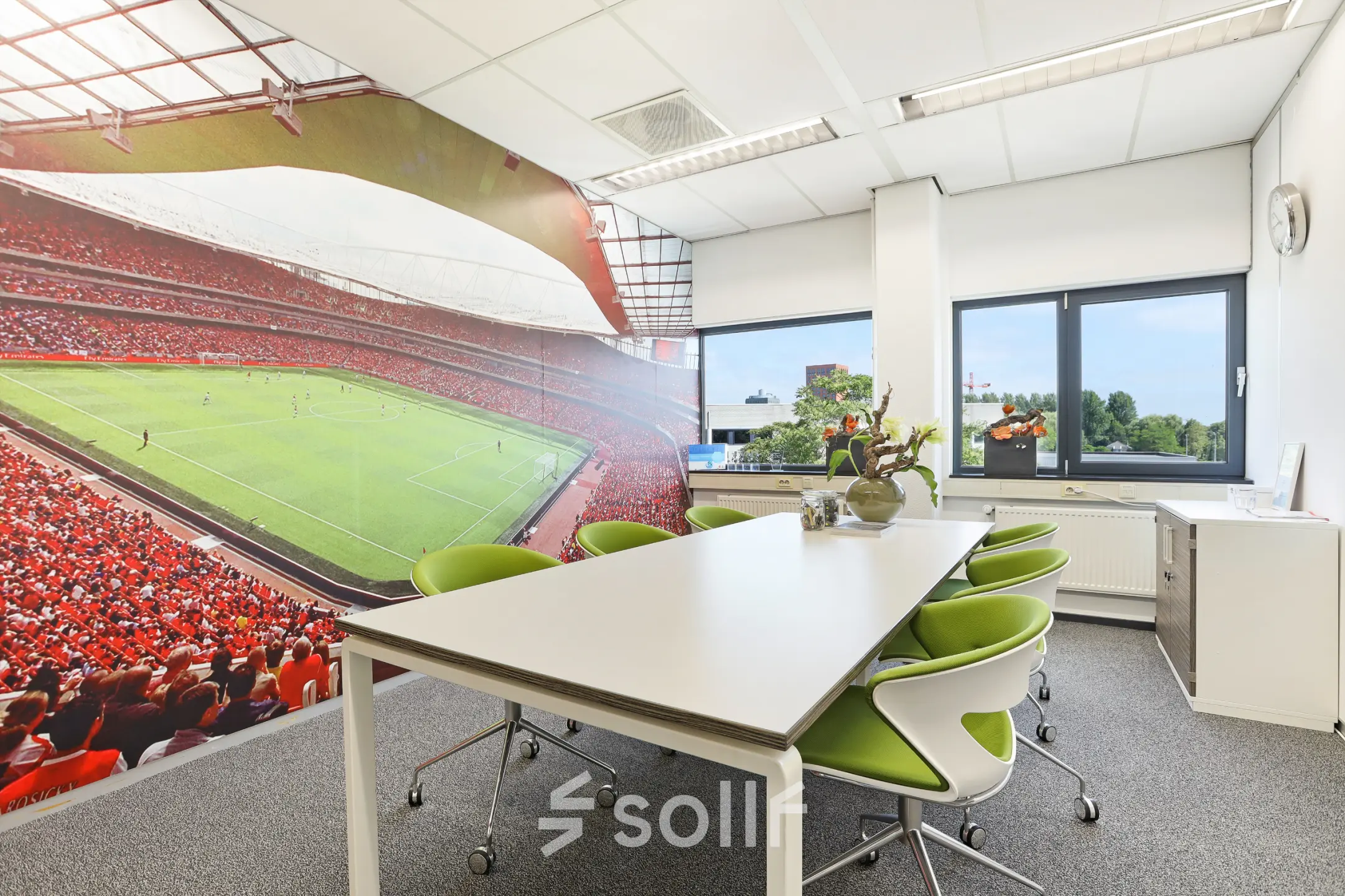 Bright office space at Winthontlaan 200, Utrecht South, featuring modern furnishings and a vibrant stadium mural, perfect for rental.