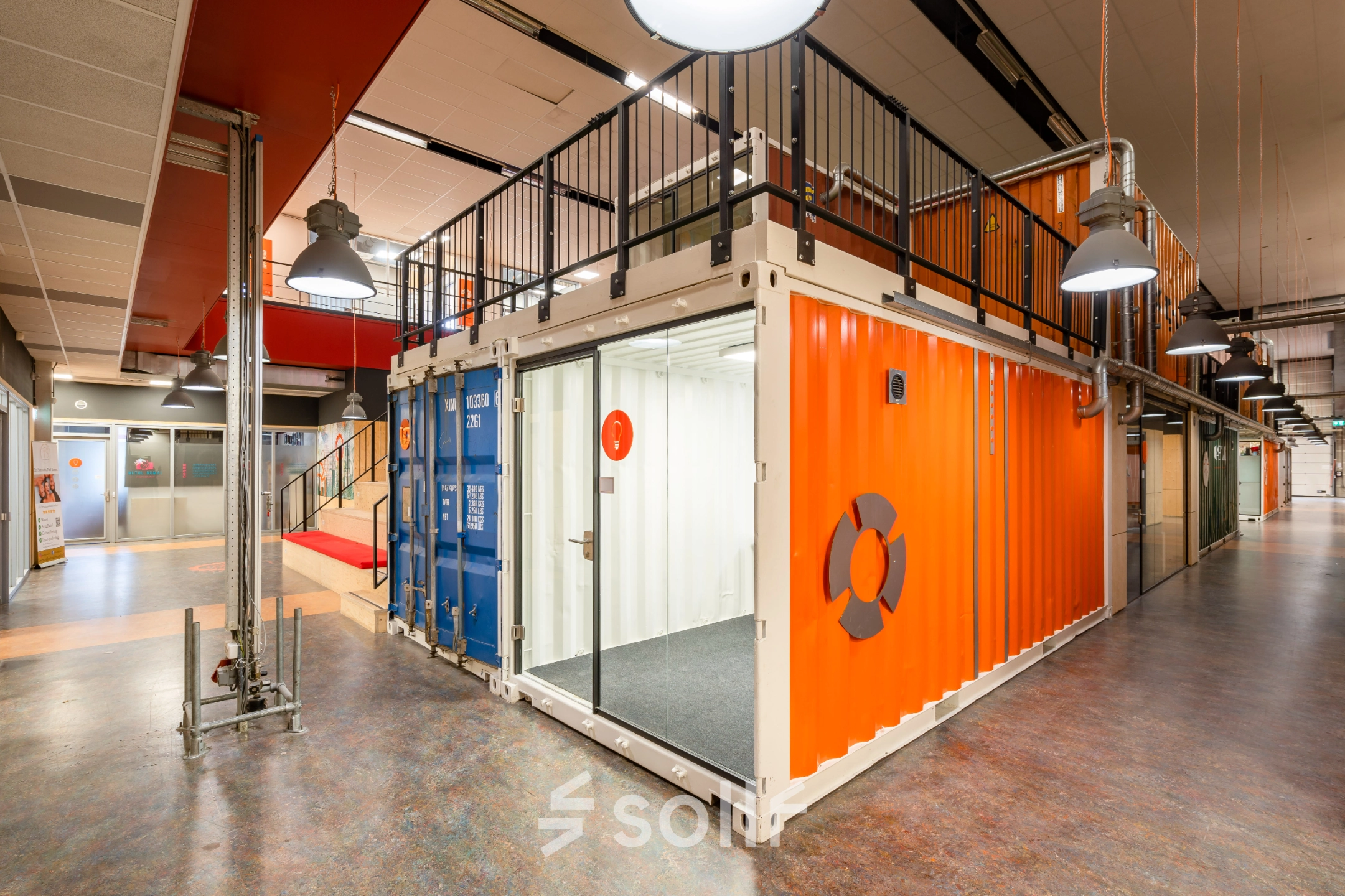 Vibrant office space interior at Proostwetering 41, Utrecht West, featuring a unique industrial design with shipping containers and bright orange accents. Ideal for office space rental, showcasing a creative and dynamic working environment.