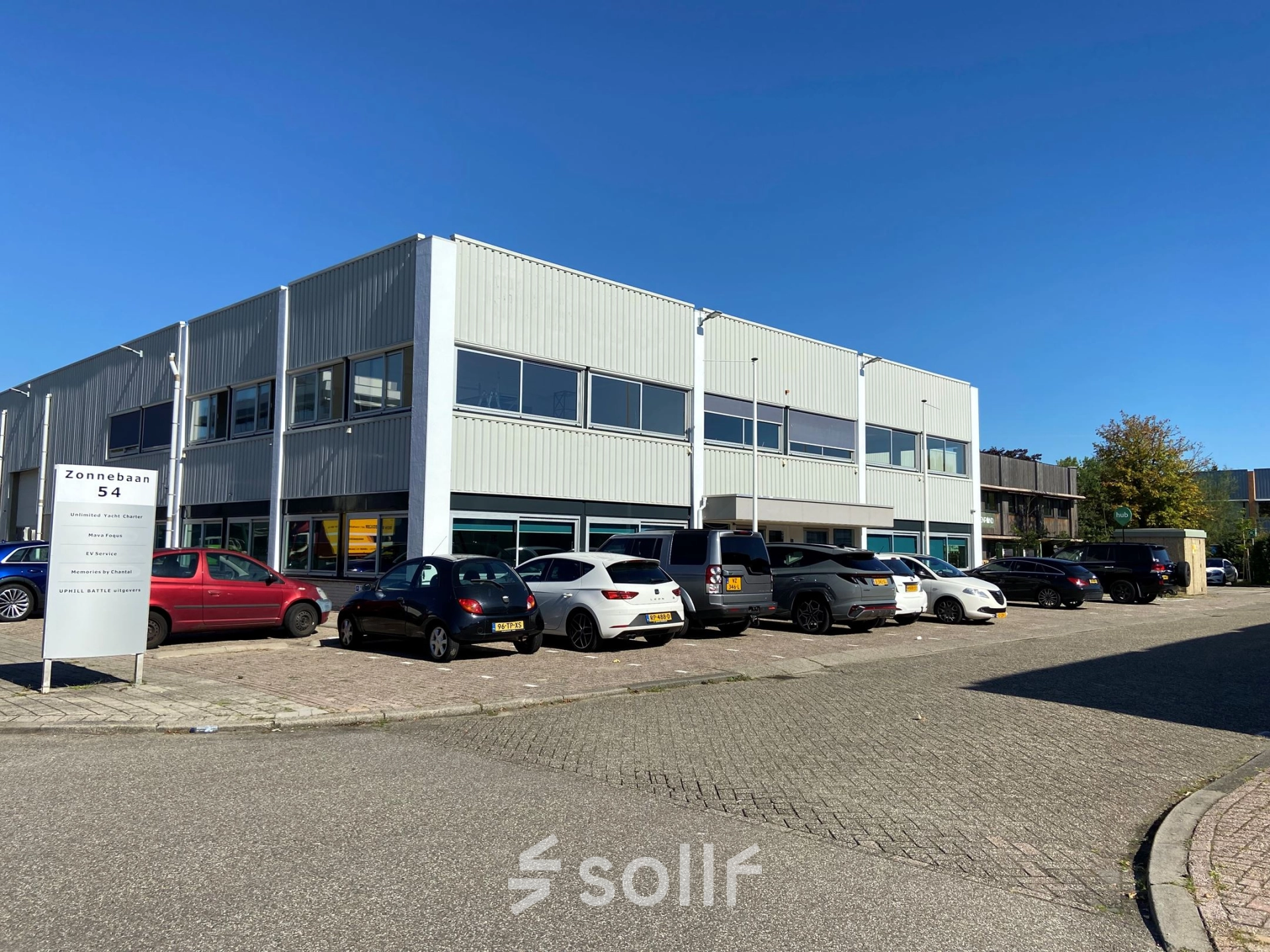 Exterior view of an office building at Zonnebaan 54, Utrecht West, suitable for office space rental. Several cars are parked outside the office to rent.