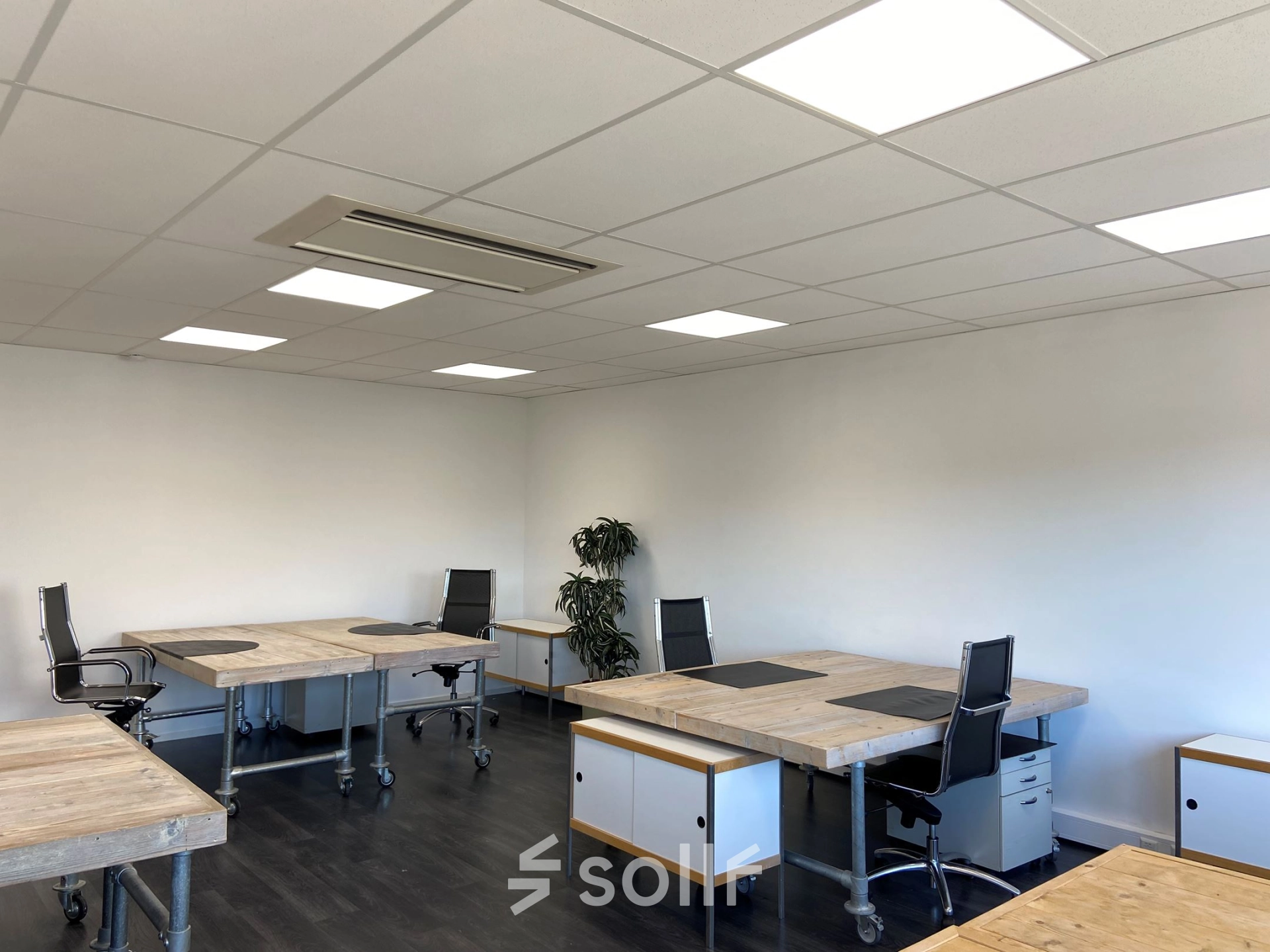 Bright office space with wooden desks and black office chairs at Zonnebaan 54, Utrecht West, ideal for those looking to rent office space. Modern lighting enhances the open, welcoming environment.