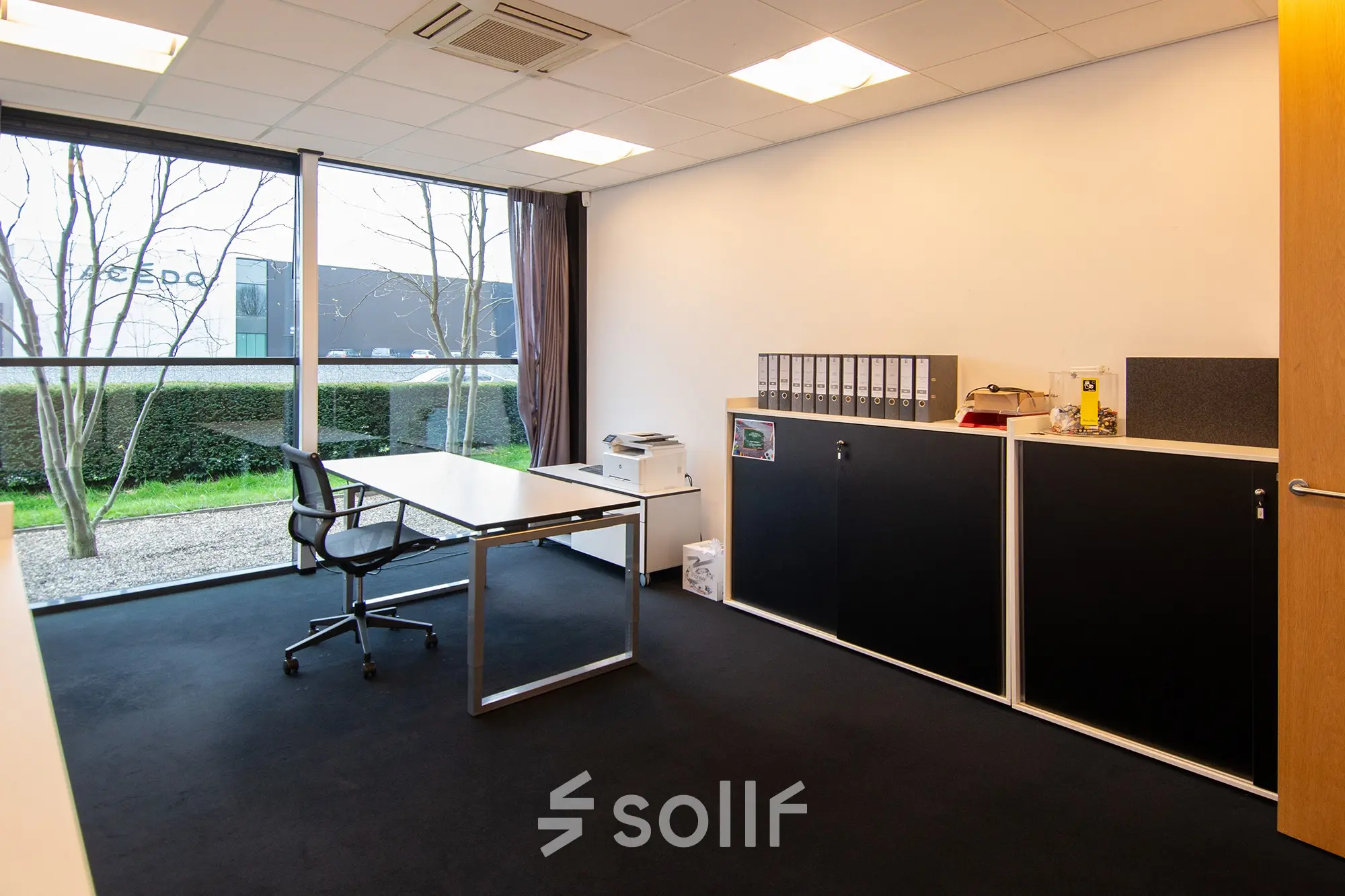 Office space rental at Gildestraat 13, Velp, featuring a bright, furnished workspace with desk, storage units, and large window offering natural light.