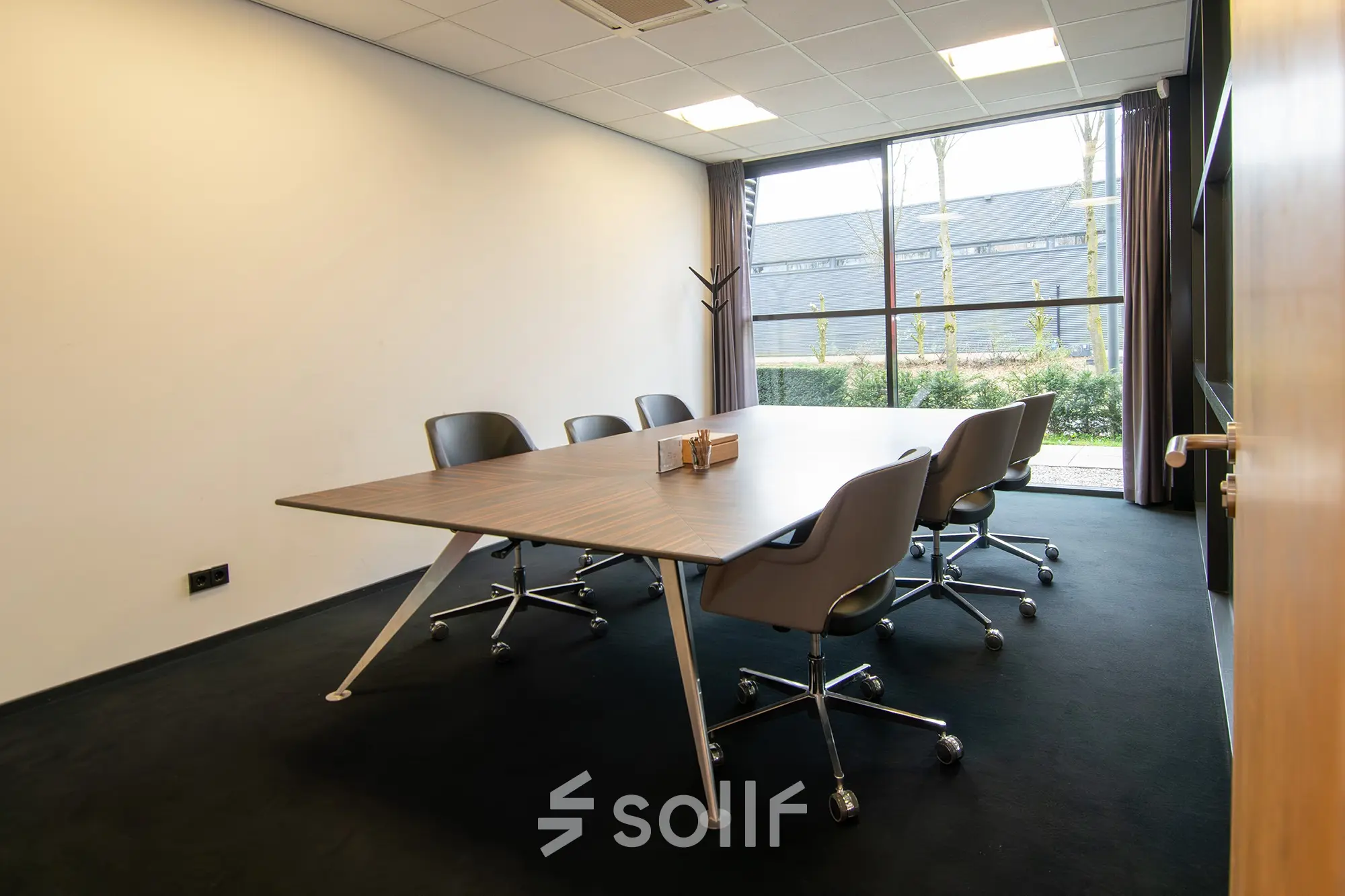 Interior office space at Gildestraat 13, Velp, featuring a modern conference table with chairs, large window, and natural light. Ideal for office space rental seekers.