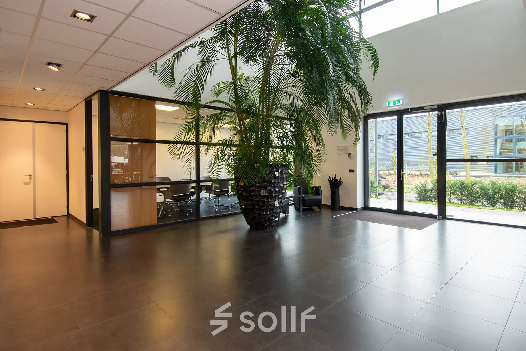 Spacious office entrance at Gildestraat 13, Velp, with a large plant and visible conference room, ideal for office space rental.