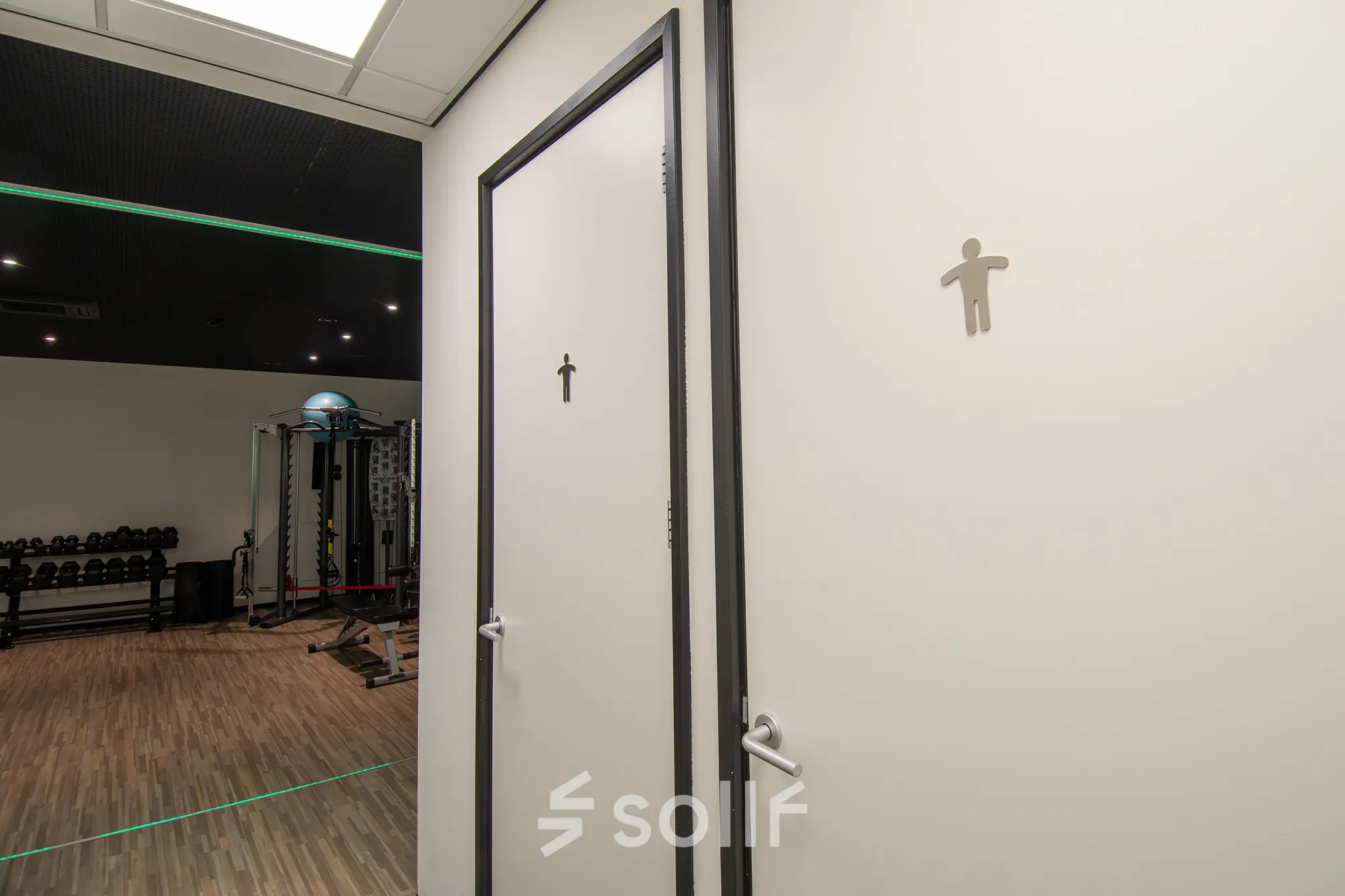 Office space at Gildestraat 13 in Velp, featuring a gym area with equipment visible near restroom doors. Ideal for an office space rental with fitness facilities.