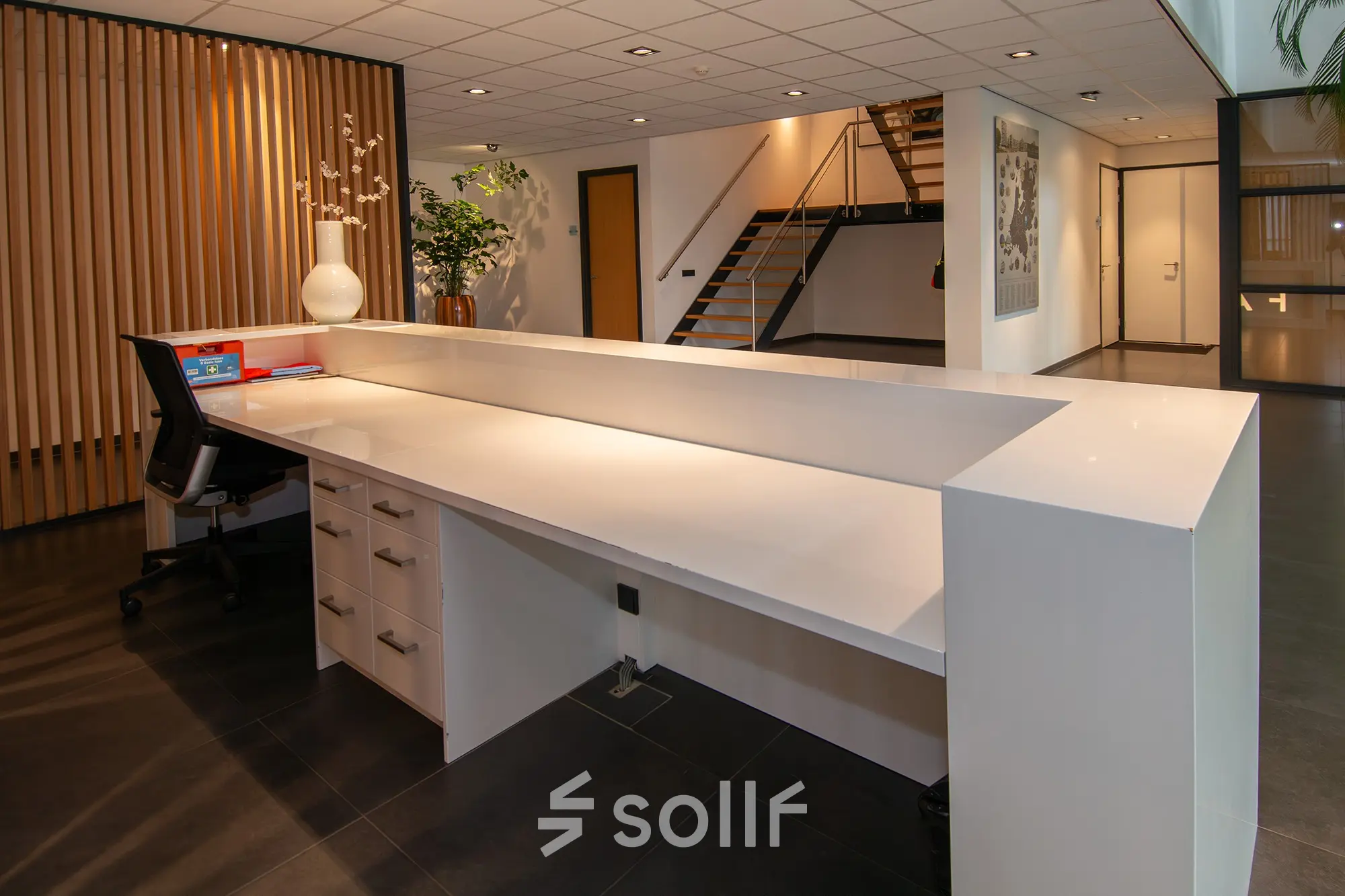 Modern reception area in an office to rent at Gildestraat 13, Velp, featuring a spacious desk with storage and contemporary design elements.
