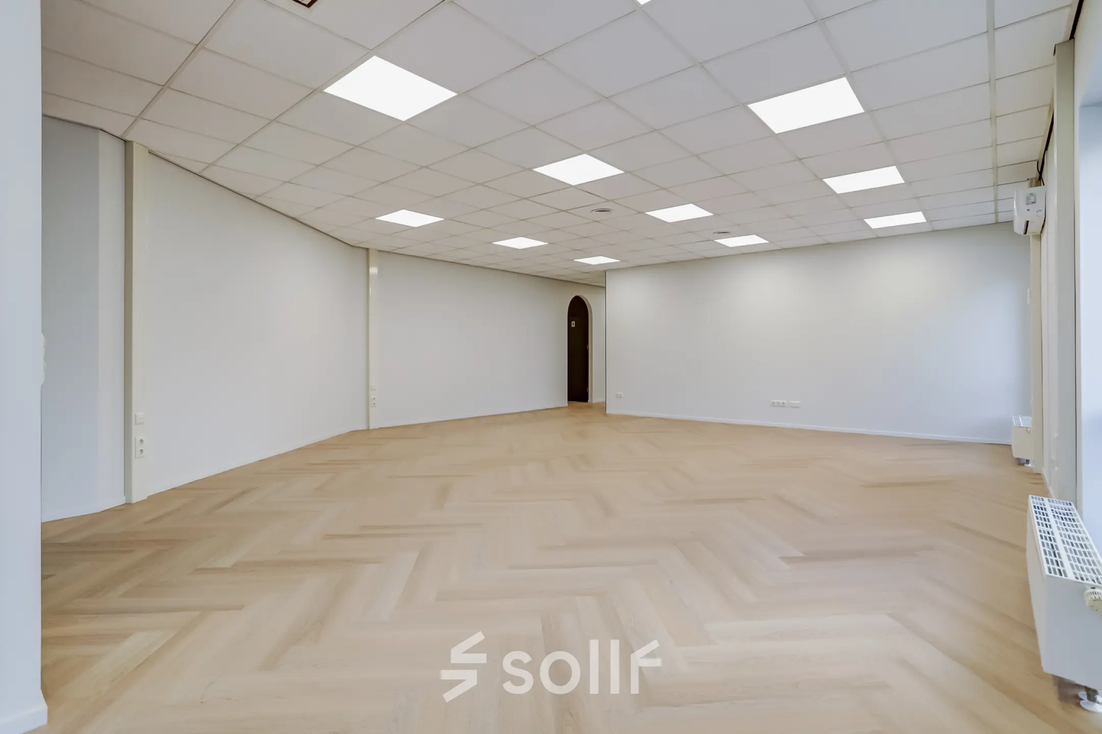 Bright office space for rent at Keizersveld 47, Venray, featuring an open floorplan with herringbone wood flooring and white walls under a grid of fluorescent lighting.