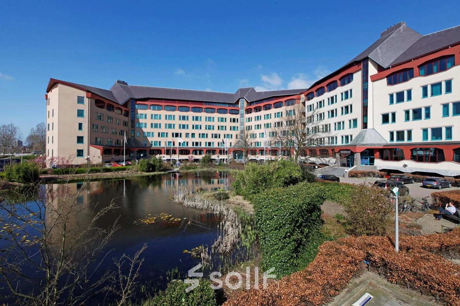 Office building exterior at Loire 104 - 206, Voorburg, with a pond in front and ample parking space available for office space rental.