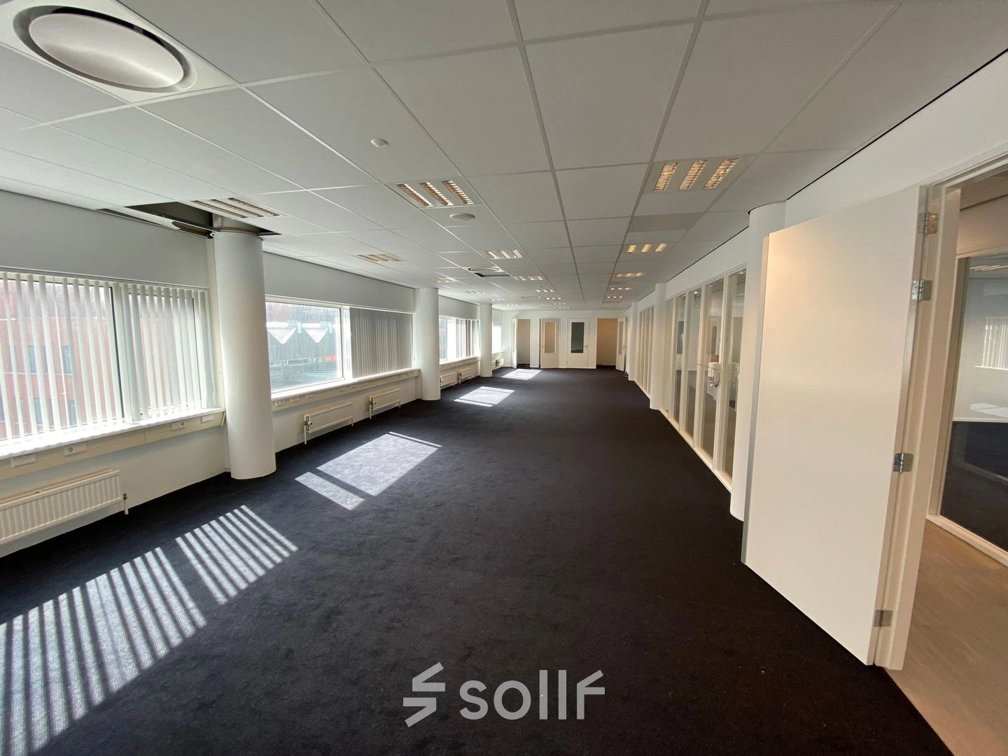 Spacious office interior at Regulusweg 11, Voorburg, featuring broad windows and neutral walls, perfect for an open-floor plan layout. Ideal for businesses seeking office space rental in a well-lit environment.