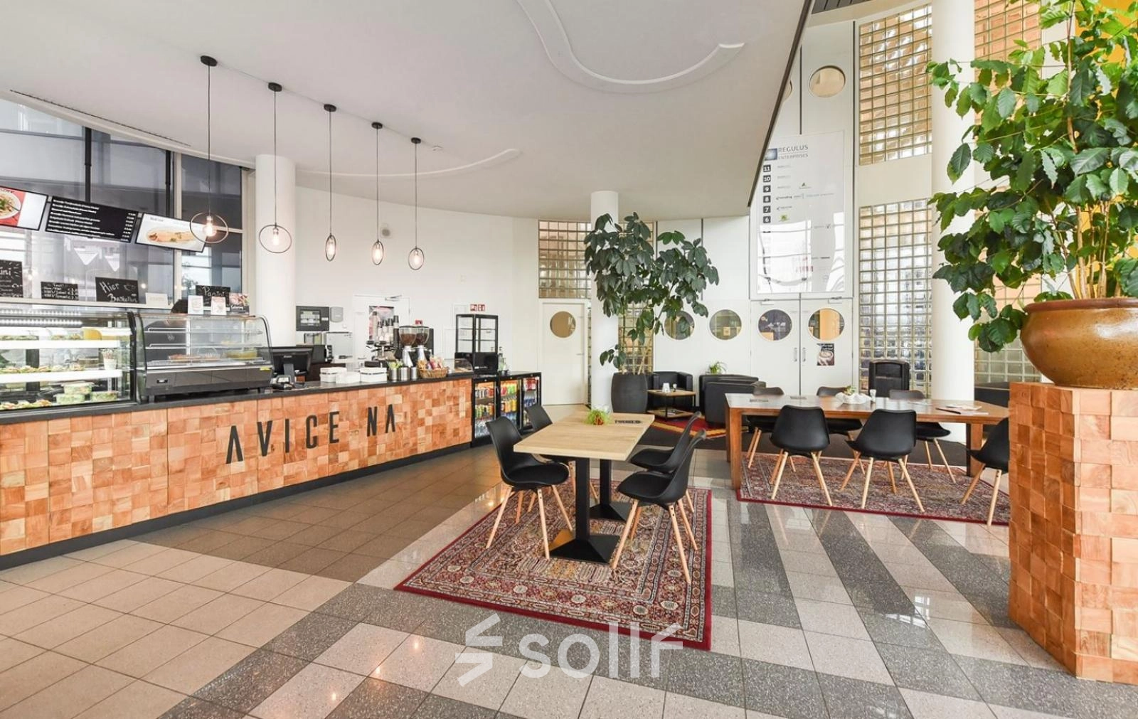 A furnished office space at Regulusweg 11, Voorburg, featuring a stylish coffee area with tables and chairs, ideal for office space rental.