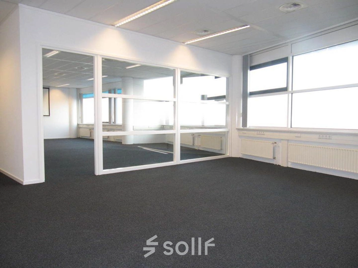 Bright, unfurnished office space available for rent at Regulusweg 11, Voorburg, featuring large windows and a glass partition for versatile office space rental options.