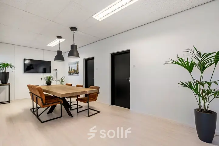 Bright office space at Agro Business Park 22, Wageningen, featuring a meeting table with chairs, plants, and modern lighting. Ideal for companies looking for office space rental.