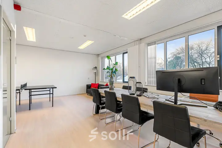 Bright office space for rent at Agro Business Park 22 in Wageningen, featuring a long wooden desk, modern chairs, and large windows providing natural light.