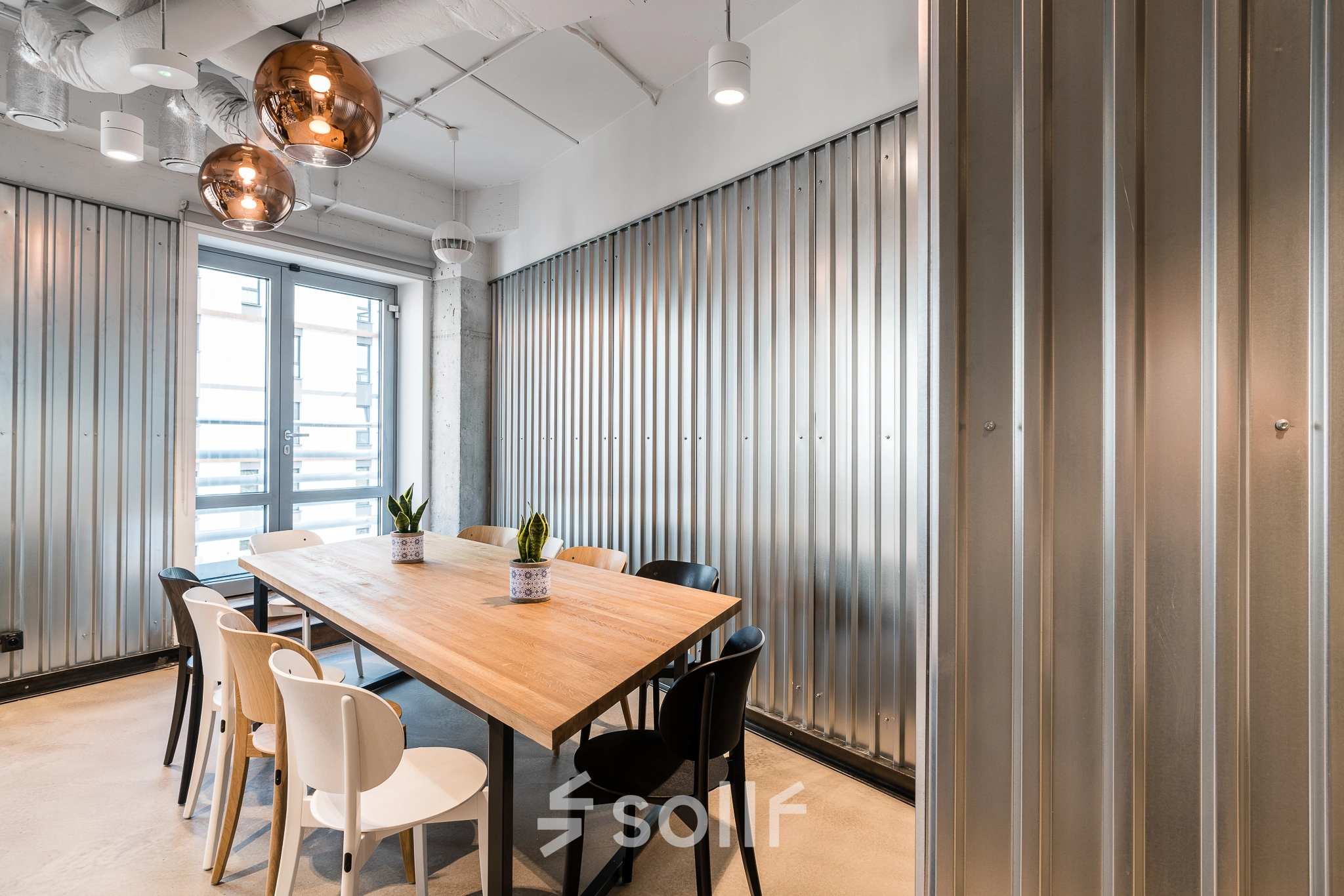 Modern conference room with a wooden table, monochrome chairs, and stylish lighting at Konstruktorska 11, a prime office space rental location in Warsaw Mokotow.
