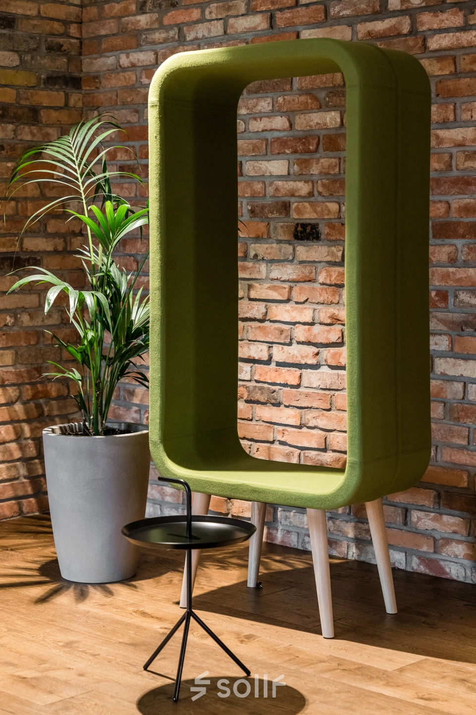 Cozy corner at the office space rental in Konstruktorska 11, Warsaw Mokotow, showcasing a modern green acoustic pod and a sleek black side table.