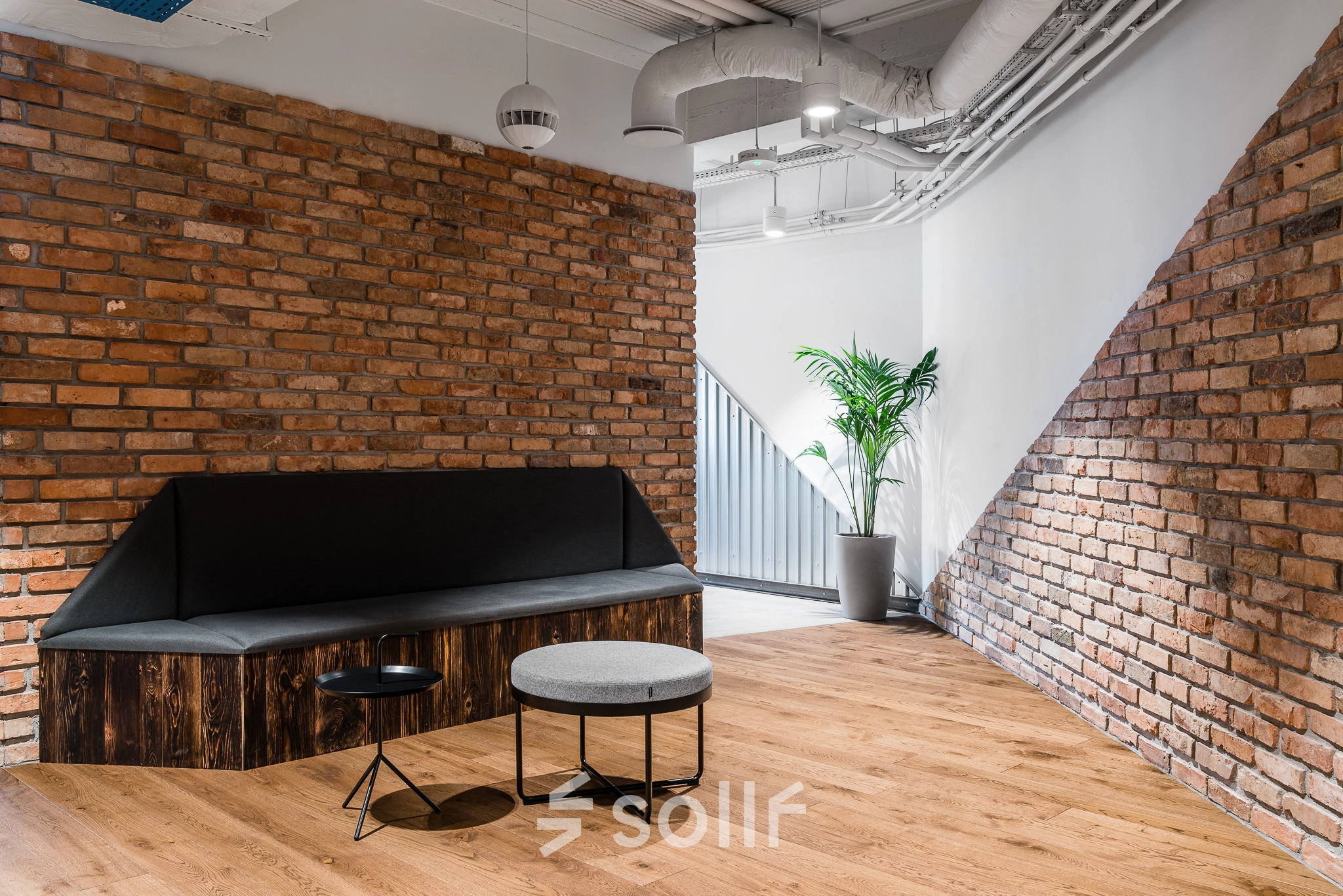 Cozy lounge area with brick walls at an office space rental on Konstruktorska 11, Warsaw Mokotow, featuring modern seating and a small table.