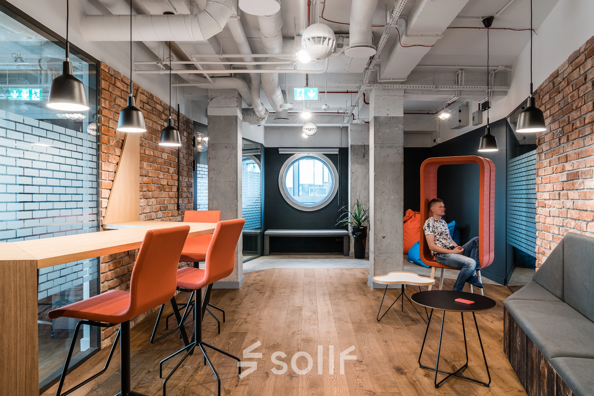 Modern office space at Konstruktorska 11, Warsaw Mokotow featuring stylish seating and a person engaged in business activities.