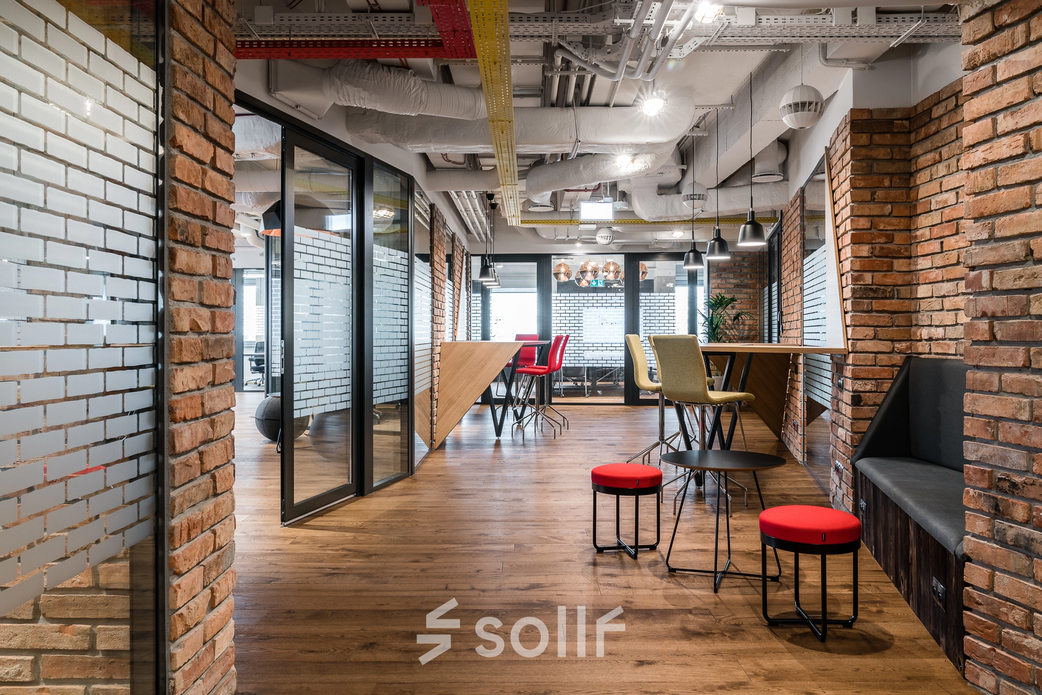 A furnished office space in Warsaw Mokotow at Konstruktorska 11, featuring stylish seating areas and brick accents, perfect for office space rental.