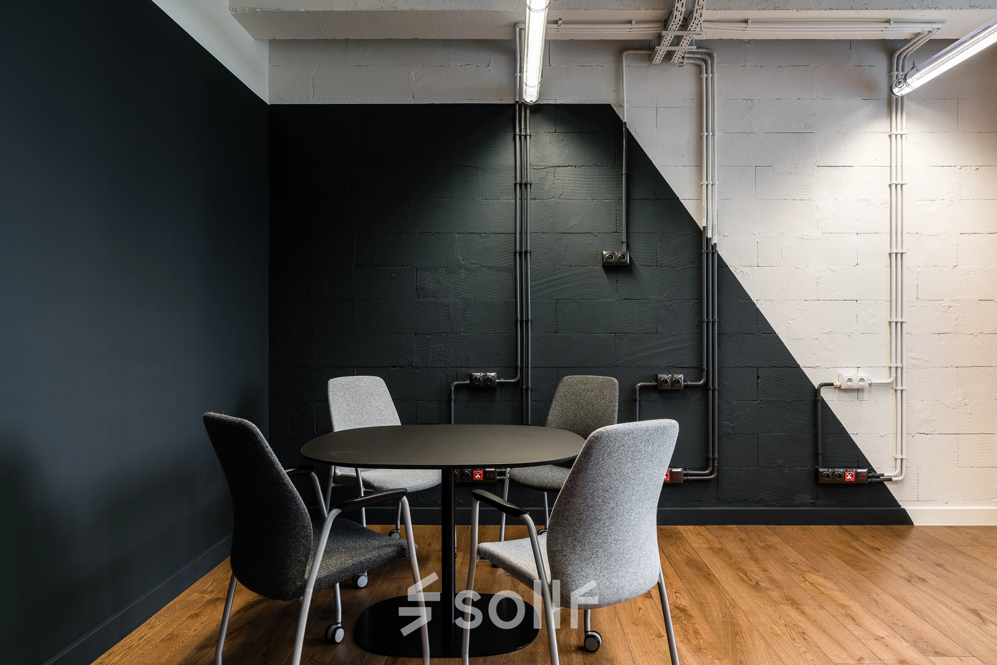 Office space rental at Konstruktorska 11, Warsaw Mokotow featuring a stylish round table and modern chairs in an industrial setting.