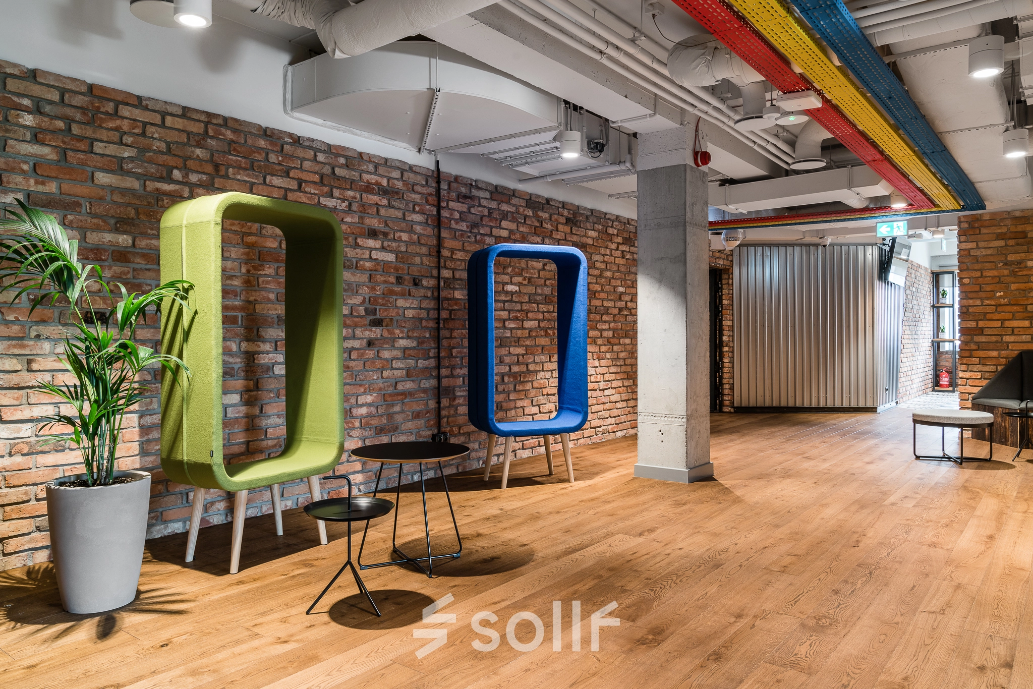 Modern office space rental in Warsaw Mokotow with colorful seating and exposed brick walls. Ideal office to rent for creative work environments.
