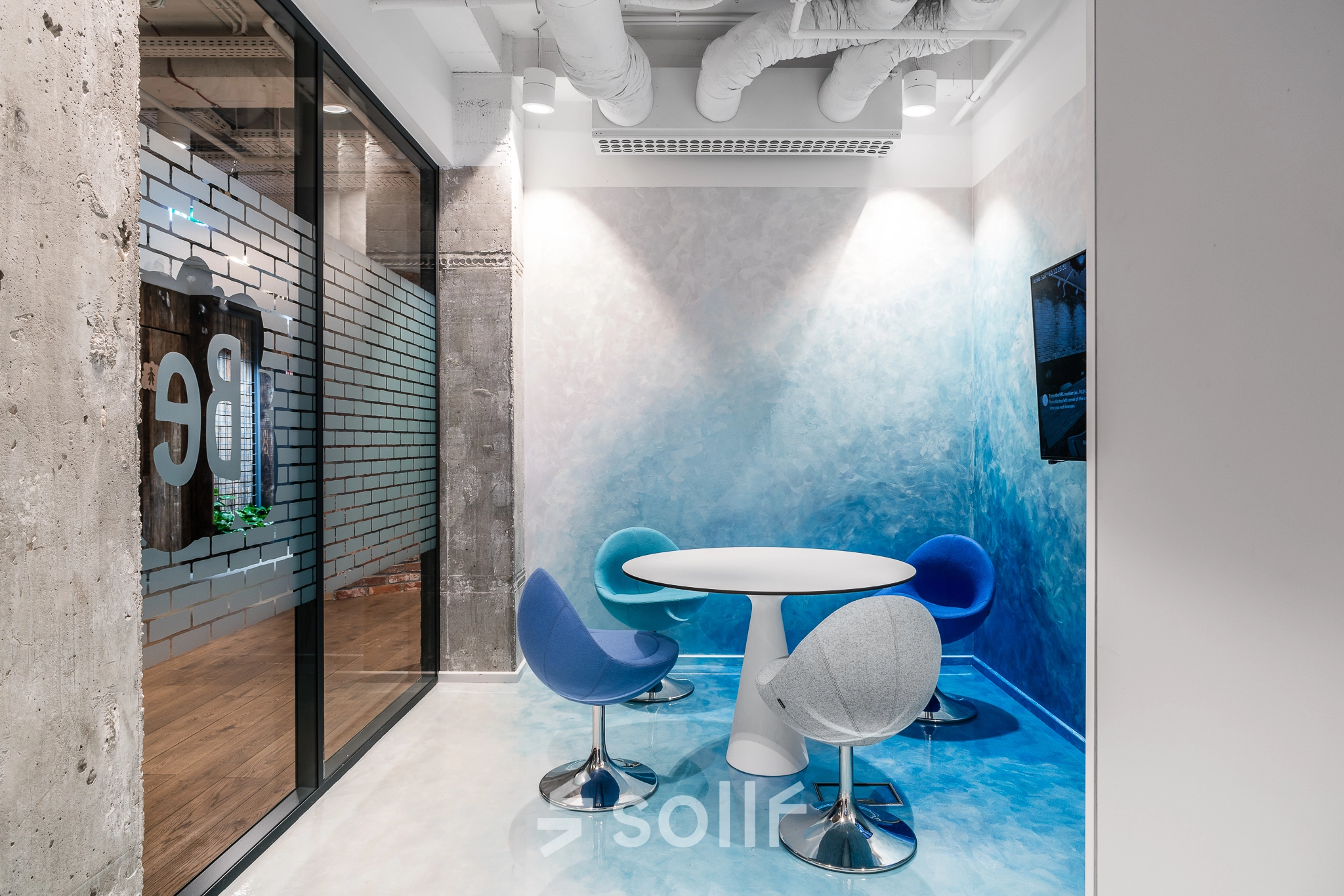 Modern office space rental at Konstruktorska 11, Warsaw Mokotow, featuring a stylish meeting area with a round table and colorful chairs.
