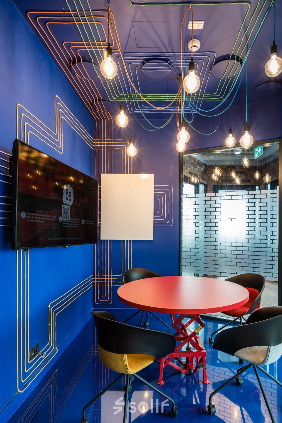 Unique and colorful meeting area with vibrant blue walls and exposed light bulbs, ideal for office space rental at Konstruktorska 11, Warsaw Mokotow.