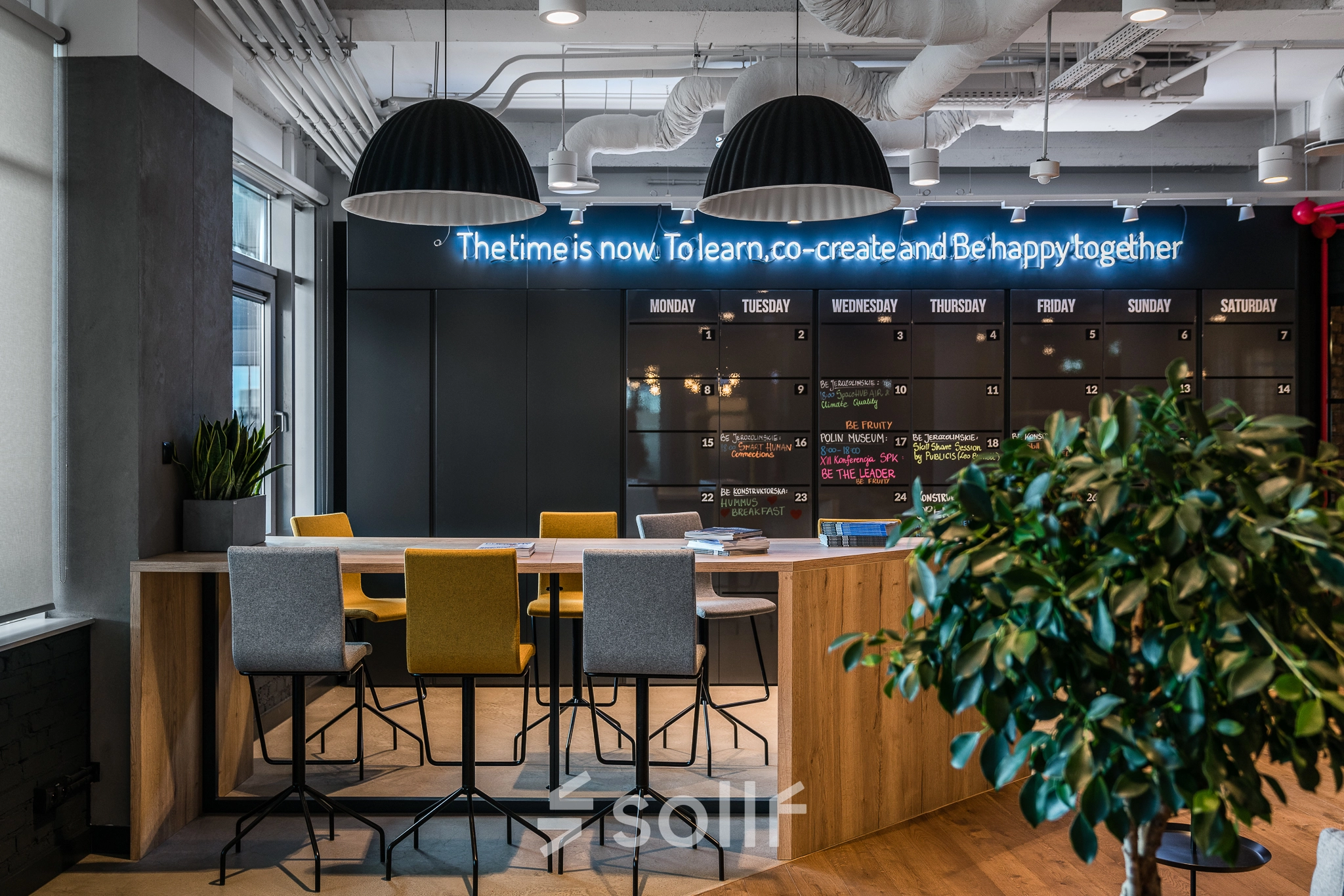 Modern workspace with high tables and chairs, accented by a neon sign, perfect for collaborative office space rental in Warsaw Mokotow.