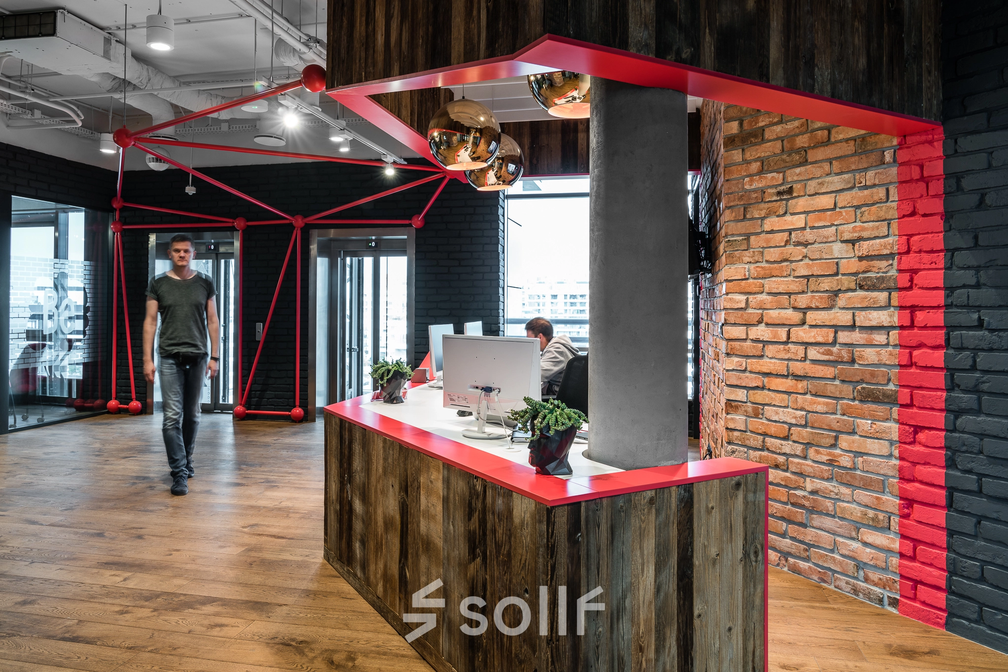 Modern office interior at Konstruktorska 11 in Warsaw Mokotow with a stylish reception desk, industrial-style décor, and a person engaged in business activity.