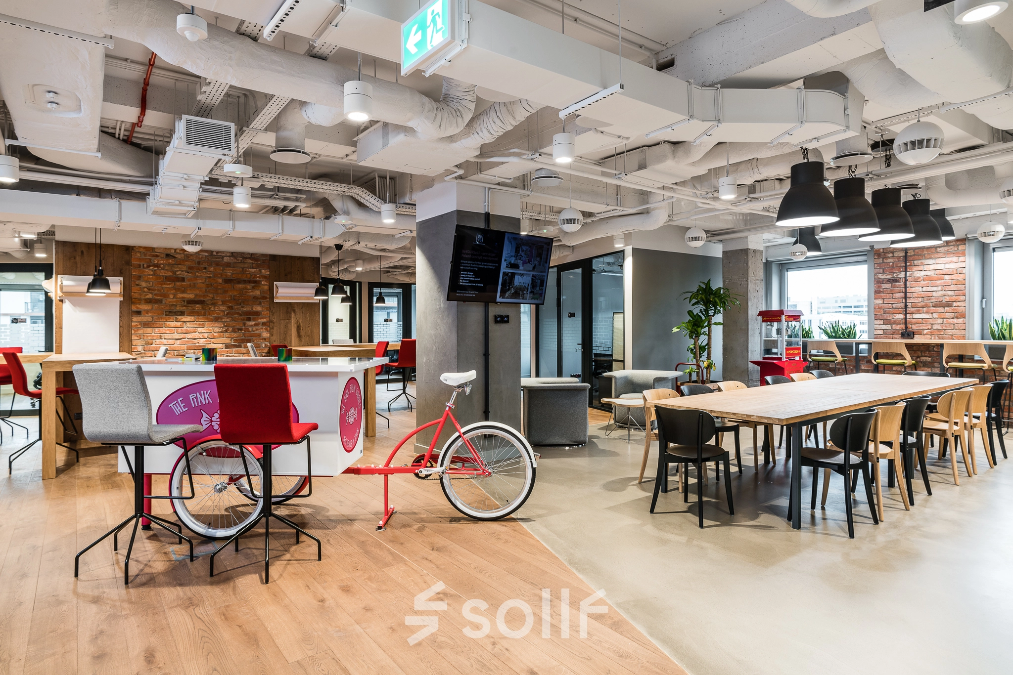 Vibrant office space at Konstruktorska 11 in Warsaw Mokotow, featuring modern furnishings, a cycle-themed bar area, and spacious seating. Ideal for office space rental.