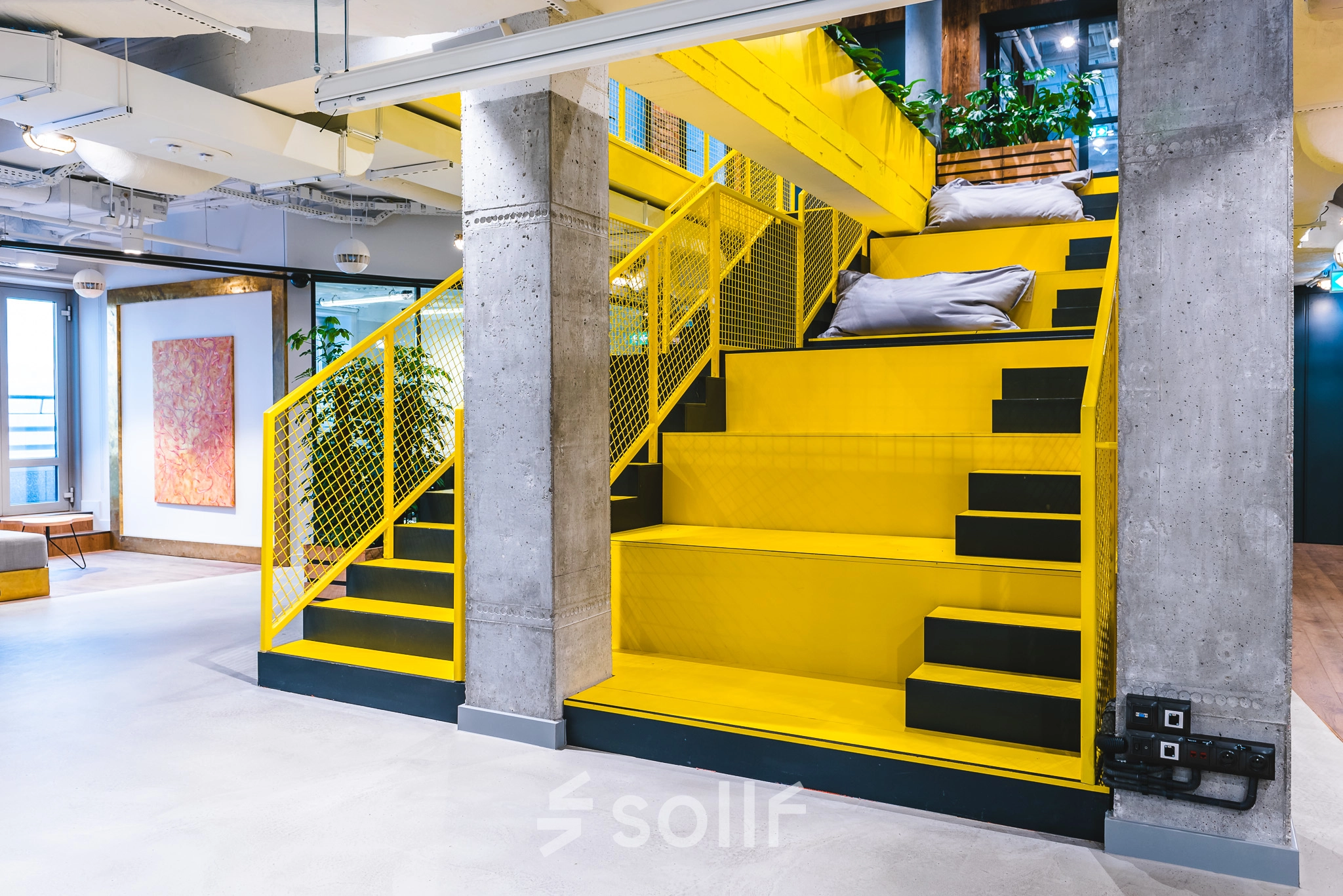Modern office interior at Konstruktorska 11 in Warsaw Mokotow featuring vibrant yellow staircases and industrial design, ideal for office space rental.