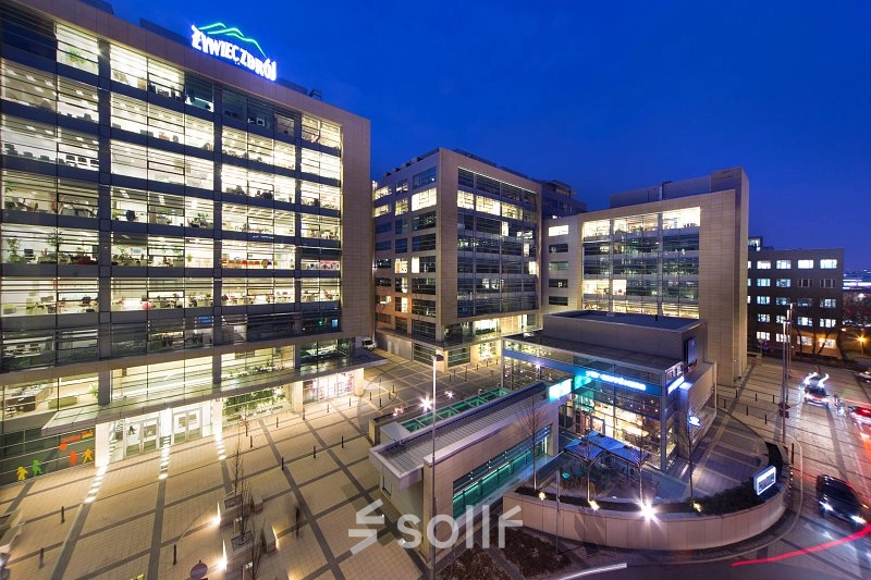 Overview of the modern office complex at Postępu 17A, Warsaw Mokotow, ideal for office space rental with illuminated buildings in the evening.