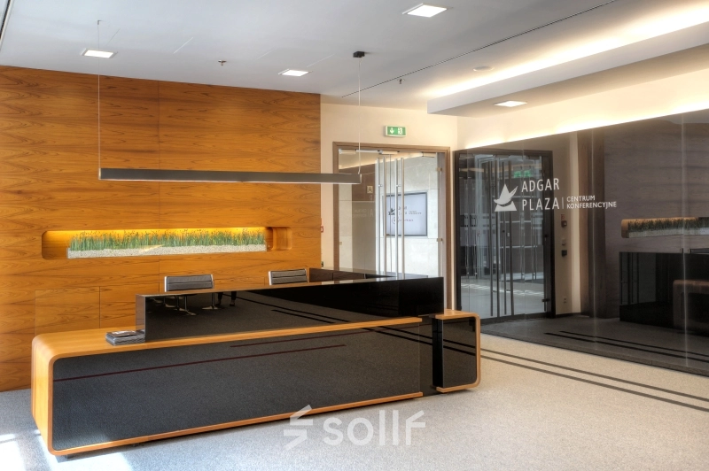 Spacious reception area at Postępu 17A, Warsaw Mokotow, ideal for office space rental, featuring a modern wooden desk and sleek decor.