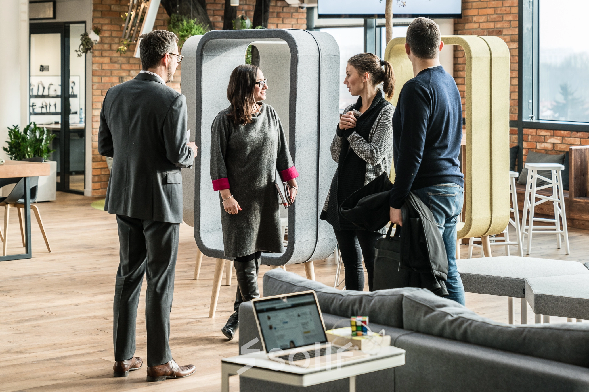 People engaging in conversation in a modern, furnished workspace, showcasing office space rental options at Al. Jerozolimskie 181B in Warsaw Ochota.