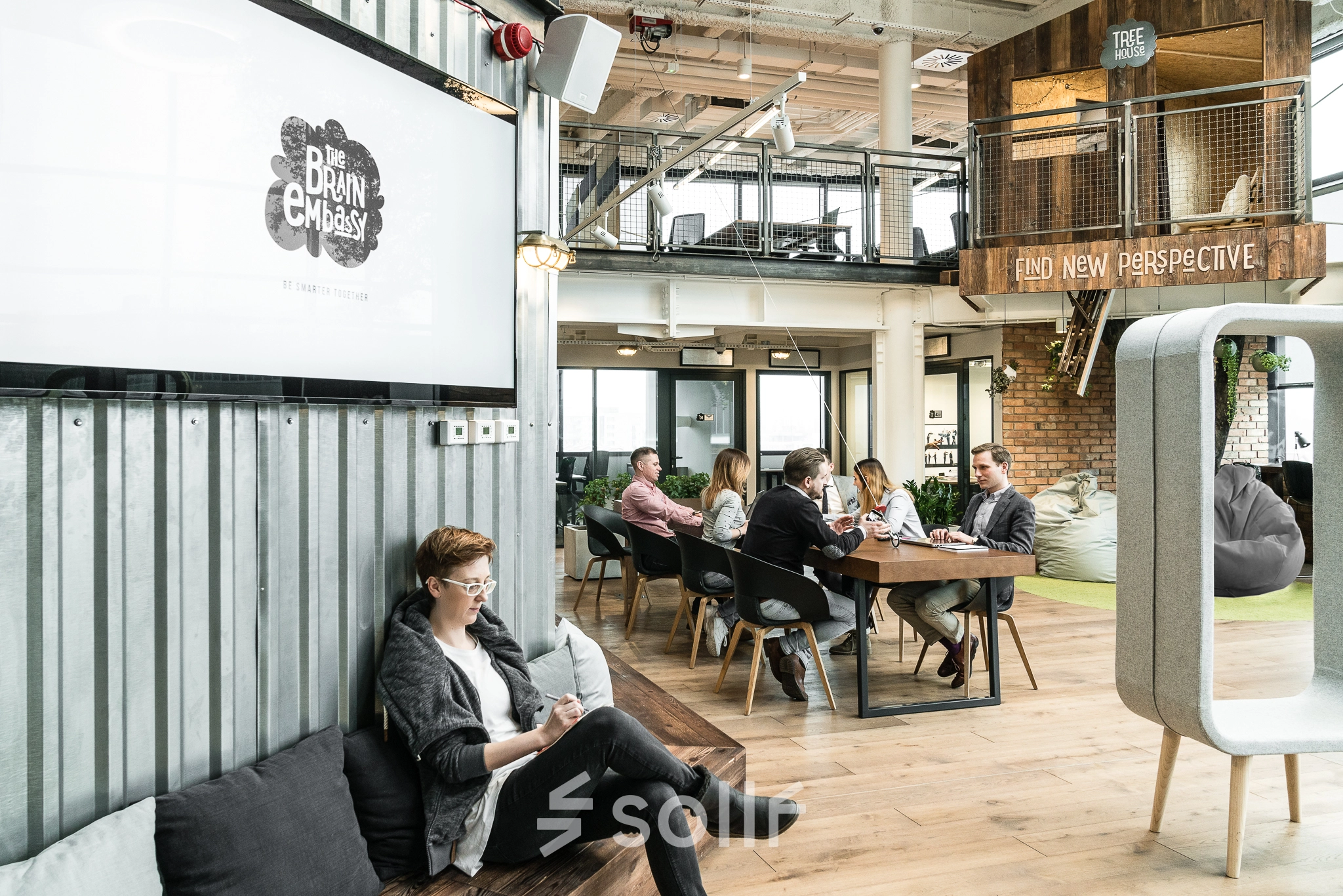 Modern office space with people engaged in discussions around tables at Al. Jerozolimskie 181B, Warsaw Ochota. Ideal for those looking to rent office space with a collaborative atmosphere.
