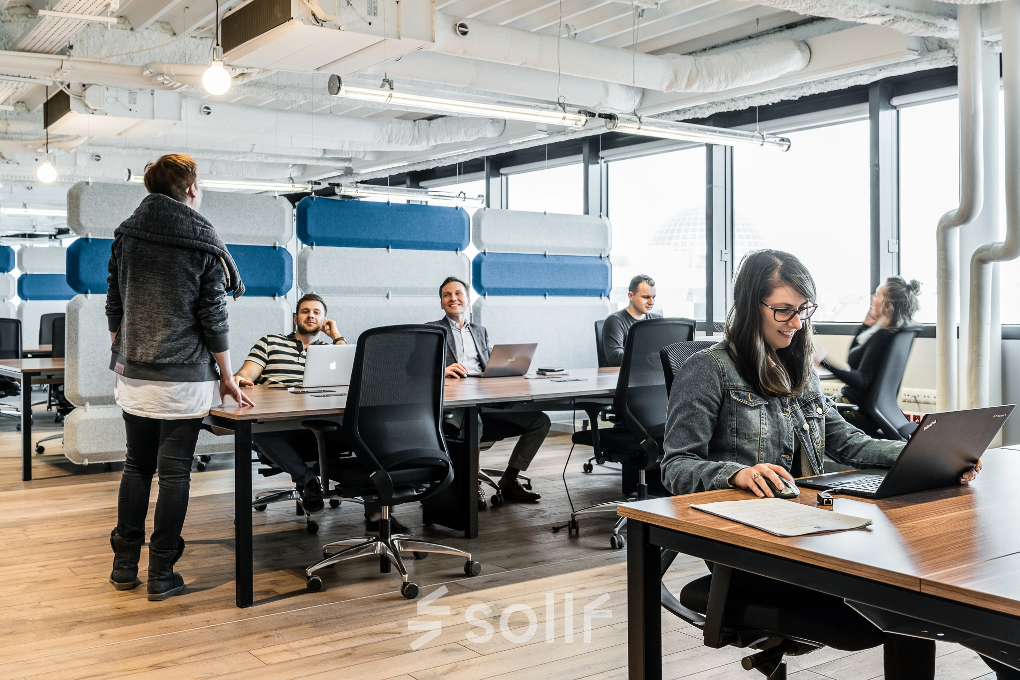 Modern office space with people working on laptops at desks, located in Warsaw Ochota, perfect for office space rental.