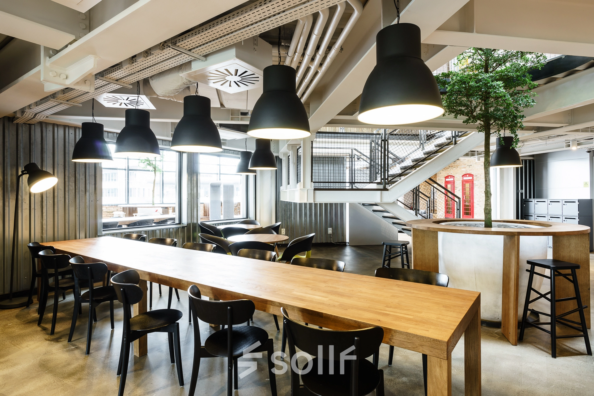 Spacious modern workspace with rows of tables and chairs under stylish lighting, suitable for office space rental in Warsaw Ochota at Al. Jerozolimskie 181B.