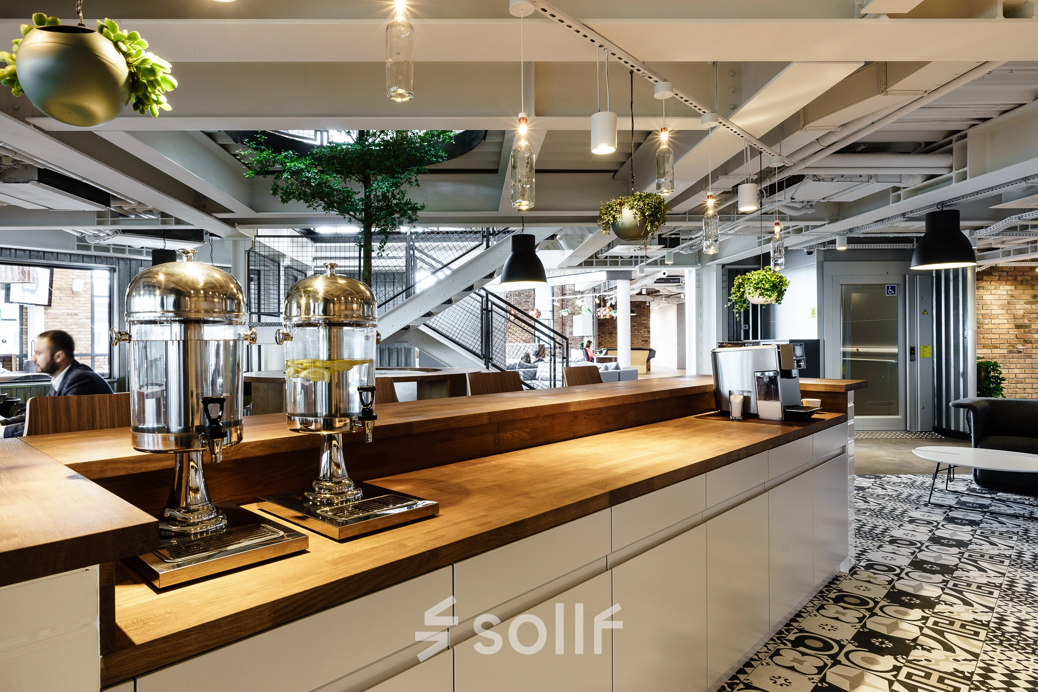 Stylish office space with modern decor in Warsaw Ochota; features a coffee station and lounge area, ideal for business meetings or as an open workspace.