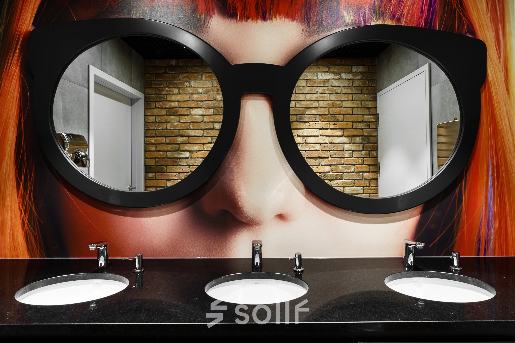 Stylish bathroom with artistic decor, mirrors shaped like large eyeglasses above three sinks. Located at Al. Jerozolimskie 181B, Warsaw Ochota, a unique office space rental opportunity.
