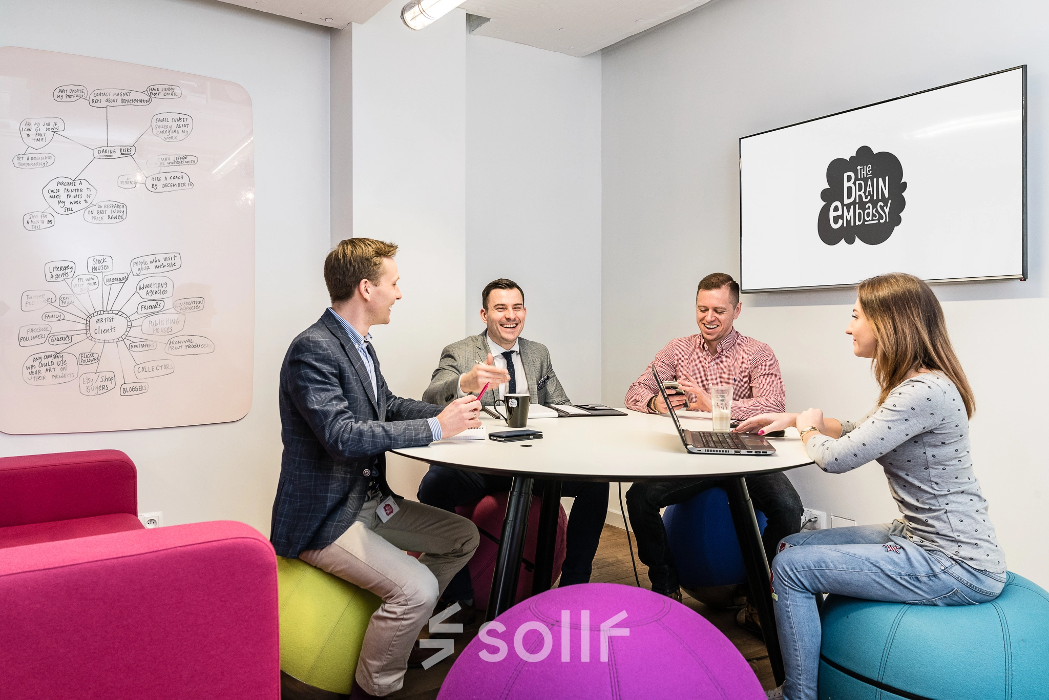 Office space for rent at Al. Jerozolimskie 181B, Warsaw Ochota, featuring a lively meeting area with professionals brainstorming and collaborating around a round table.