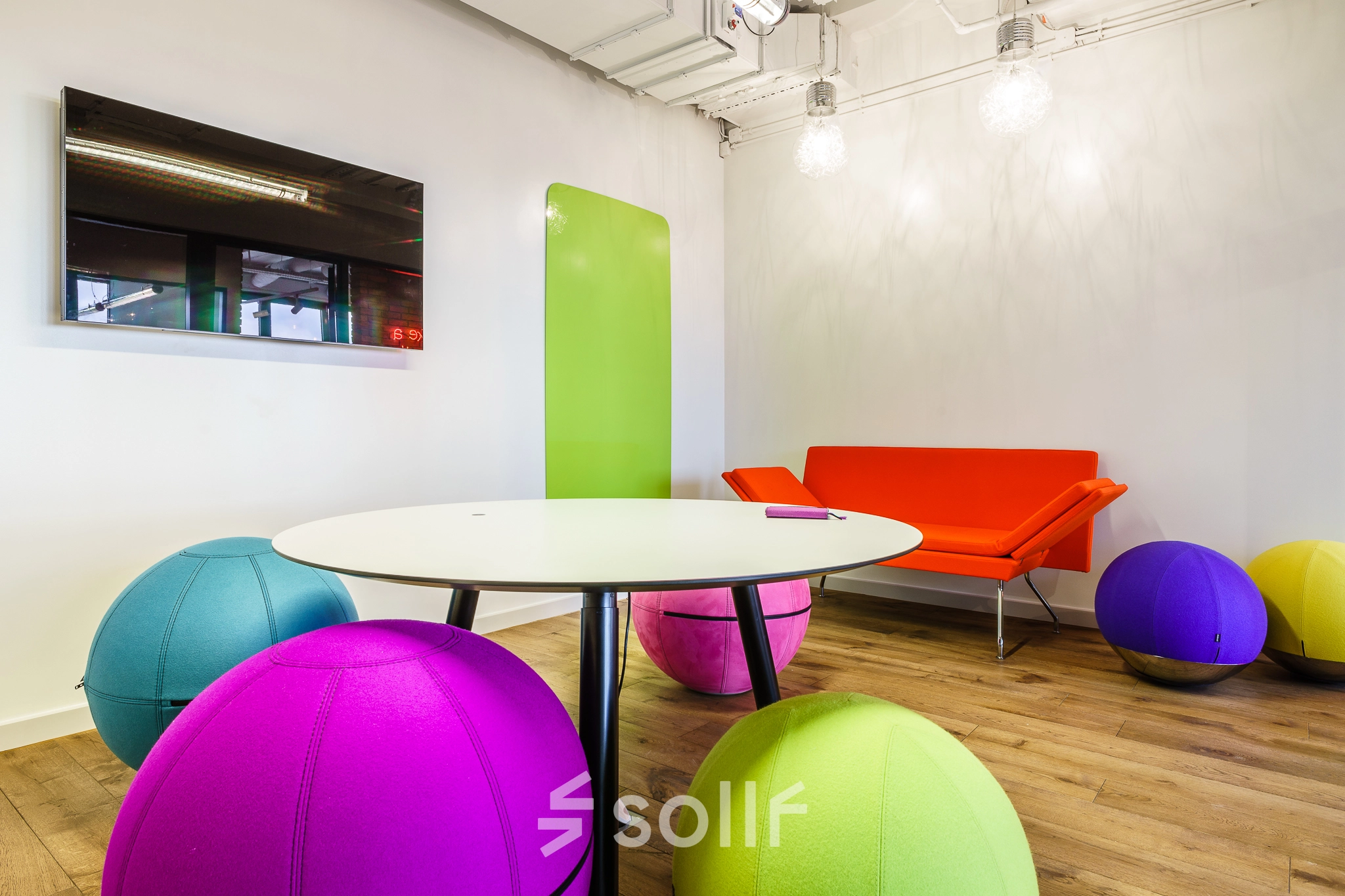 Bright and colorful office space with a round table and vibrant seating, part of an office to rent in Warsaw Ochota.
