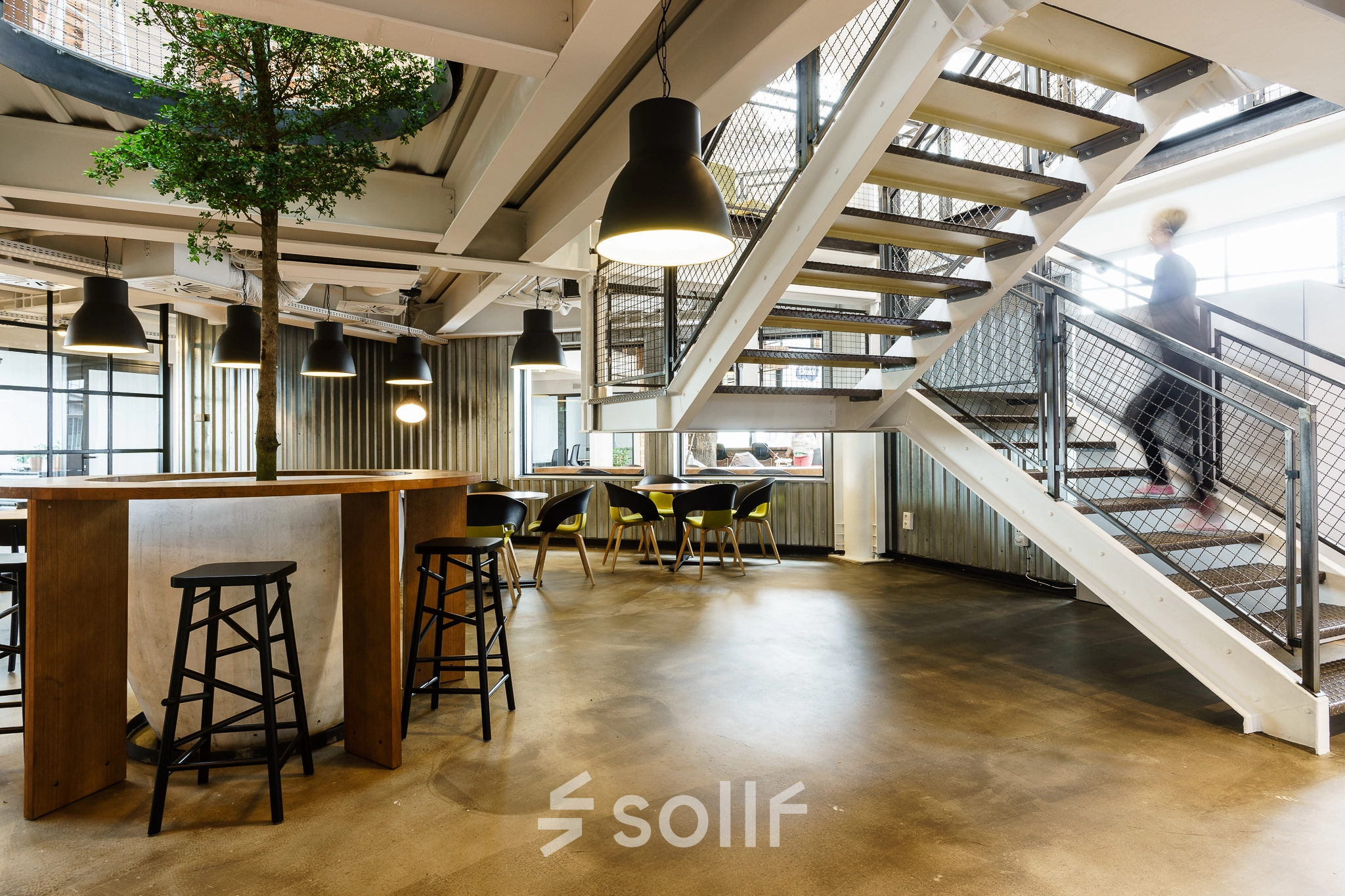 Modern office space with high ceilings and open floorplan at Al. Jerozolimskie 181B, Warsaw Ochota. A person is casually walking up the stairs.